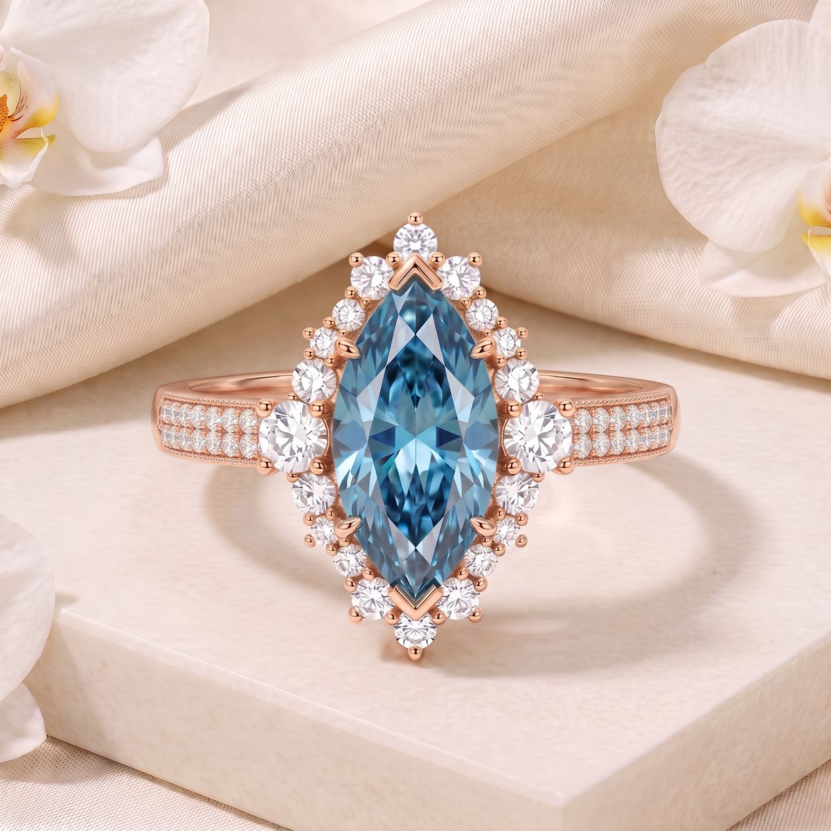 Rose gold marquise cut blue moissanite halo ring displayed on a white marble platform.