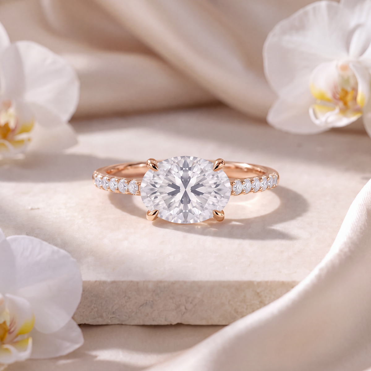 Rose gold east-west oval moissanite engagement ring with a pave diamond band.