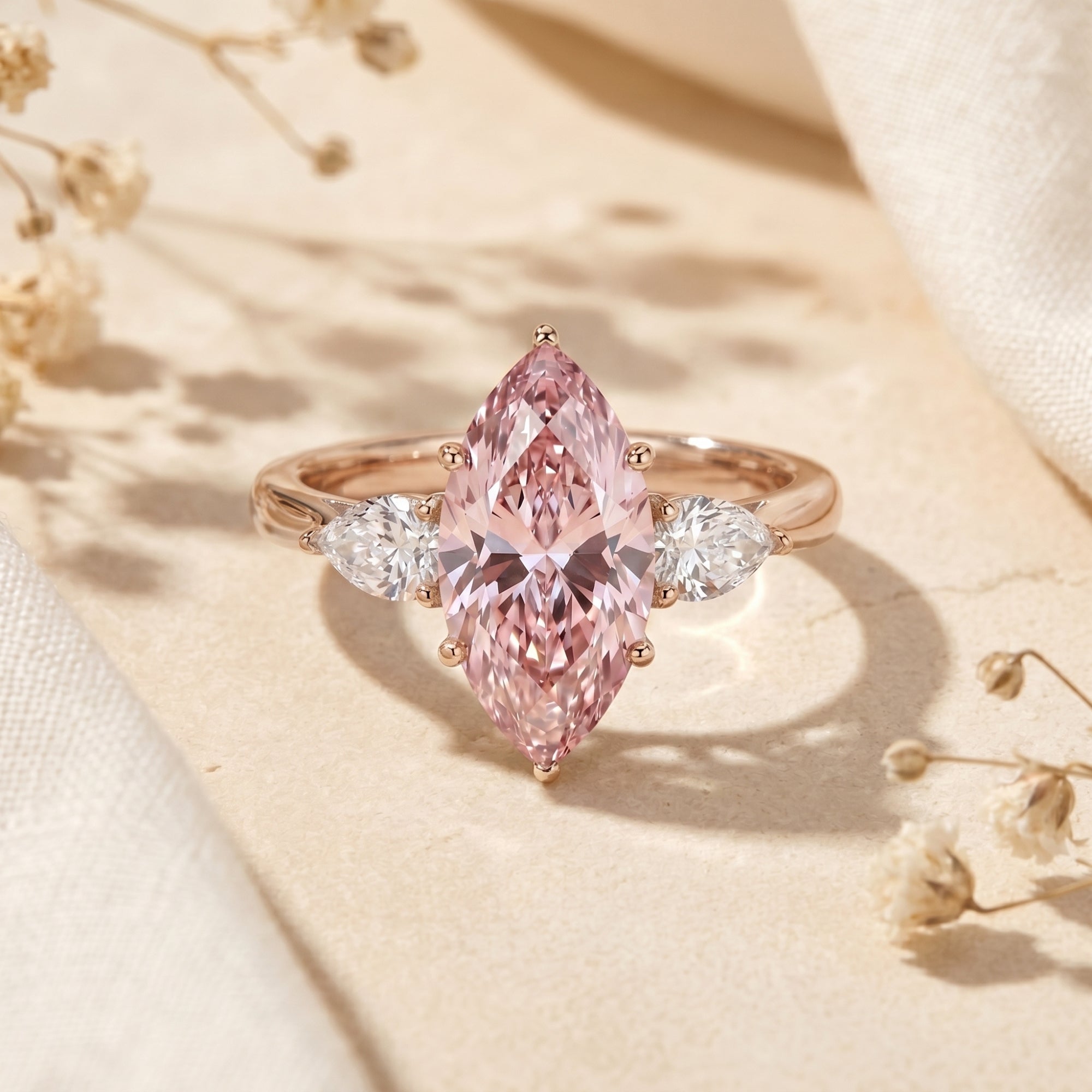 Marquise pink moissanite rose gold promise ring with pear side stones on a lifestyle background.