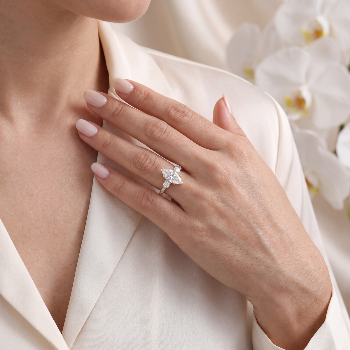 Model wearing the yellow gold marquise moissanite three-stone ring held near her collar.