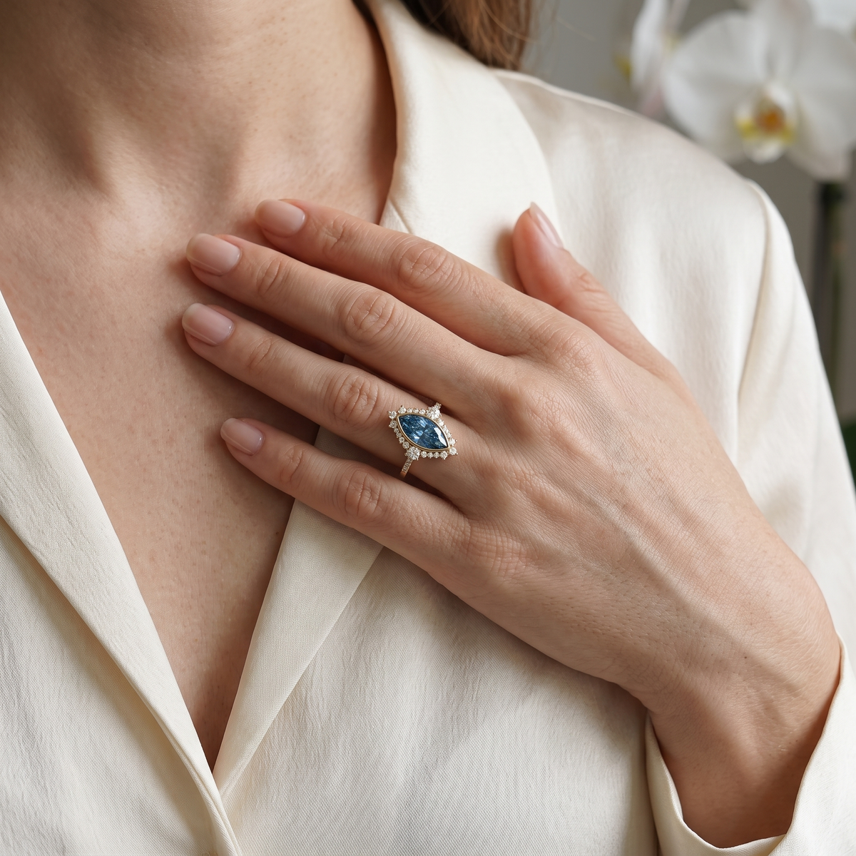 Lifestyle view of a woman wearing a vintage-inspired marquise blue gemstone halo ring in rose gold.