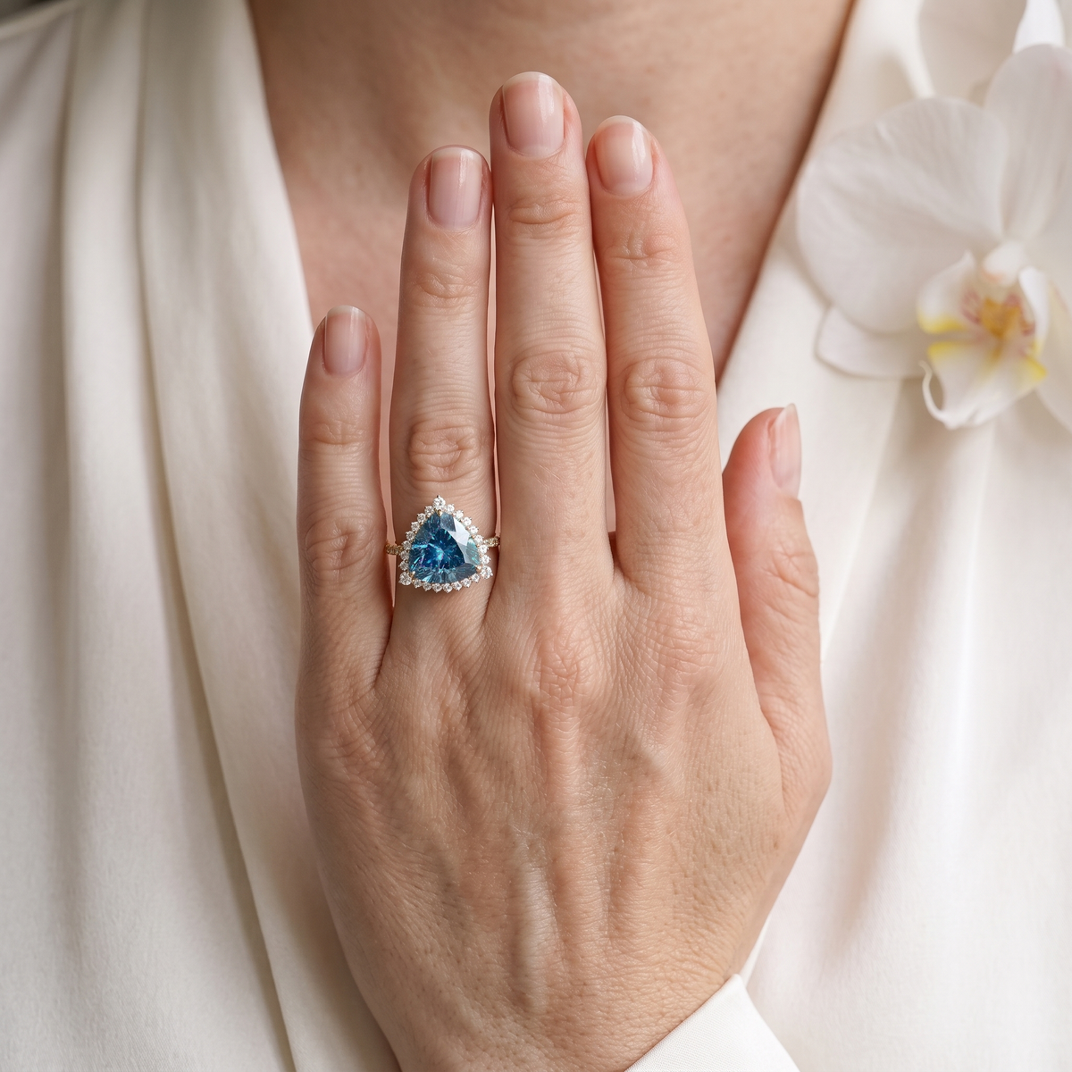 Model wearing a trillion-cut blue moissanite halo ring in rose gold.