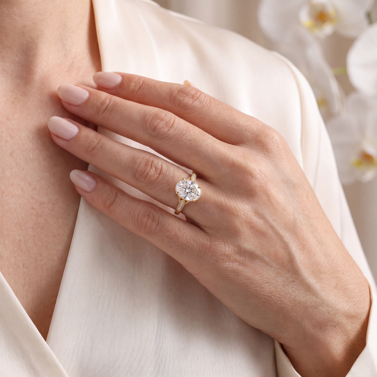 Model wearing the yellow gold oval moissanite ring against a silk blouse.