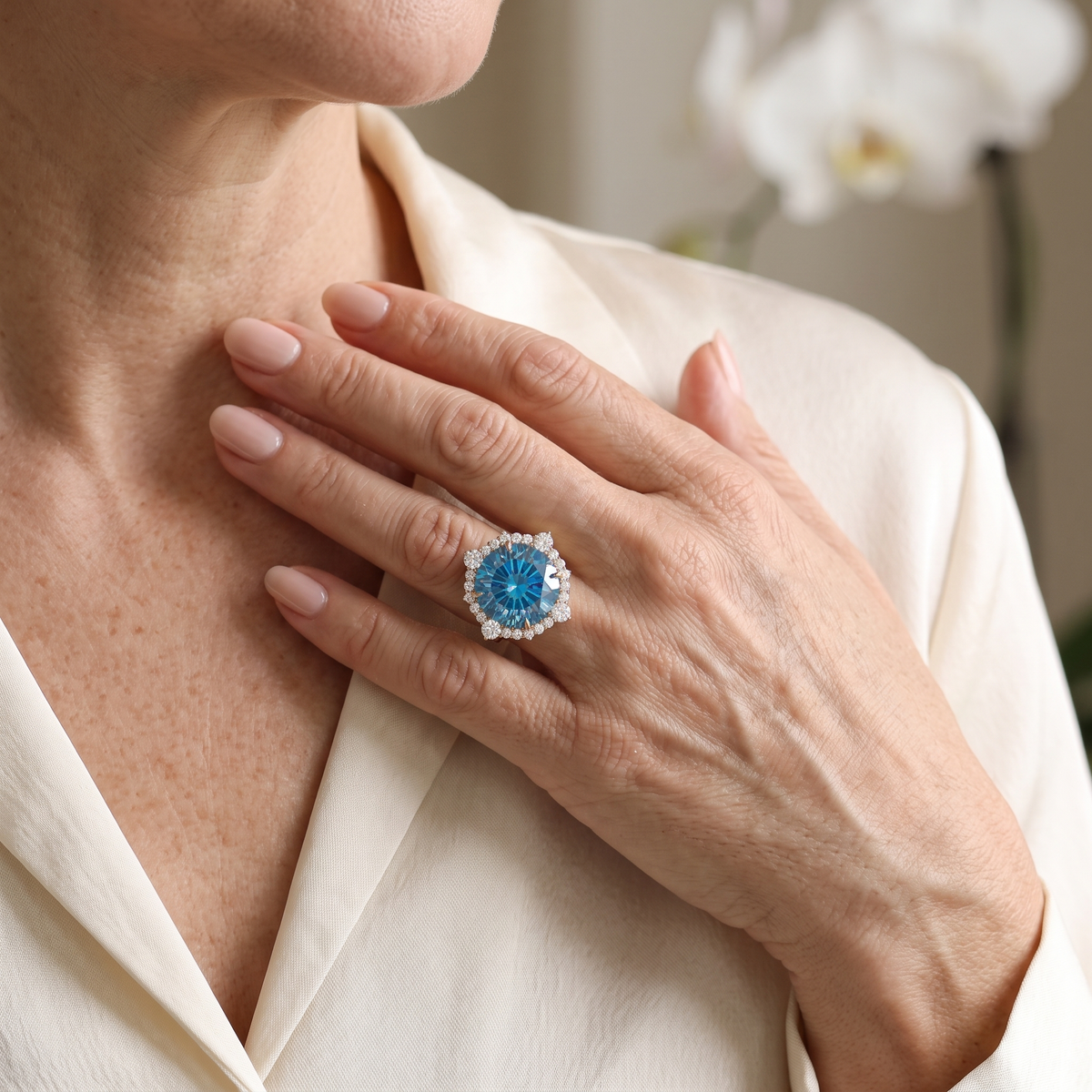 Model wearing a rose gold blue moissanite halo ring resting her hand near her collarbone.