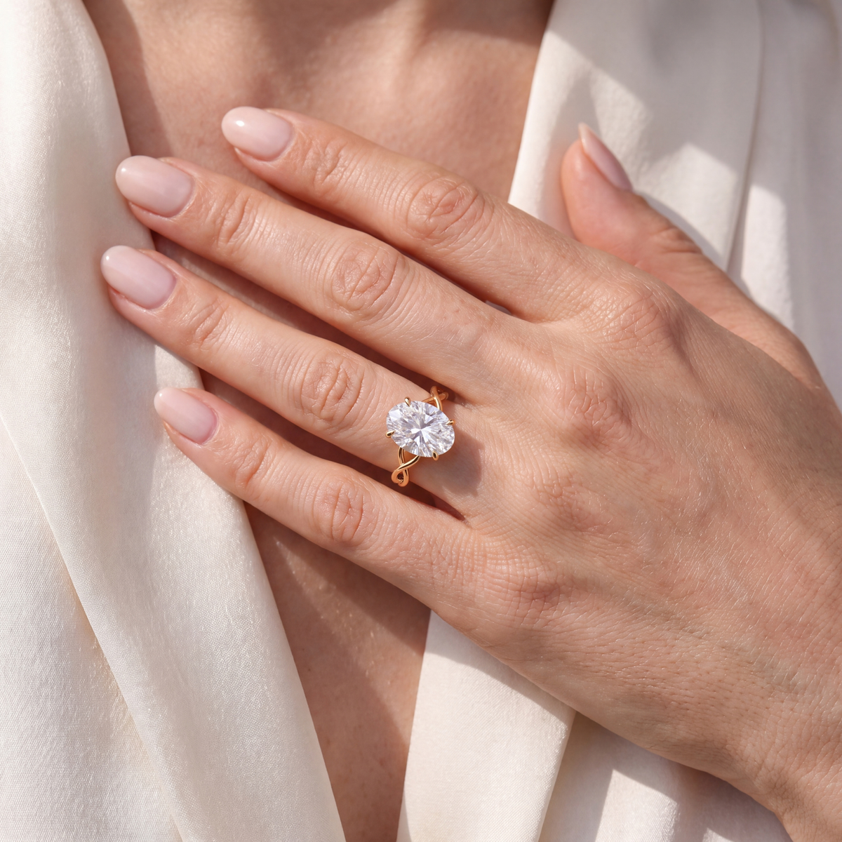 A close-up shot of an oval moissanite yellow gold engagement ring worn on a hand.