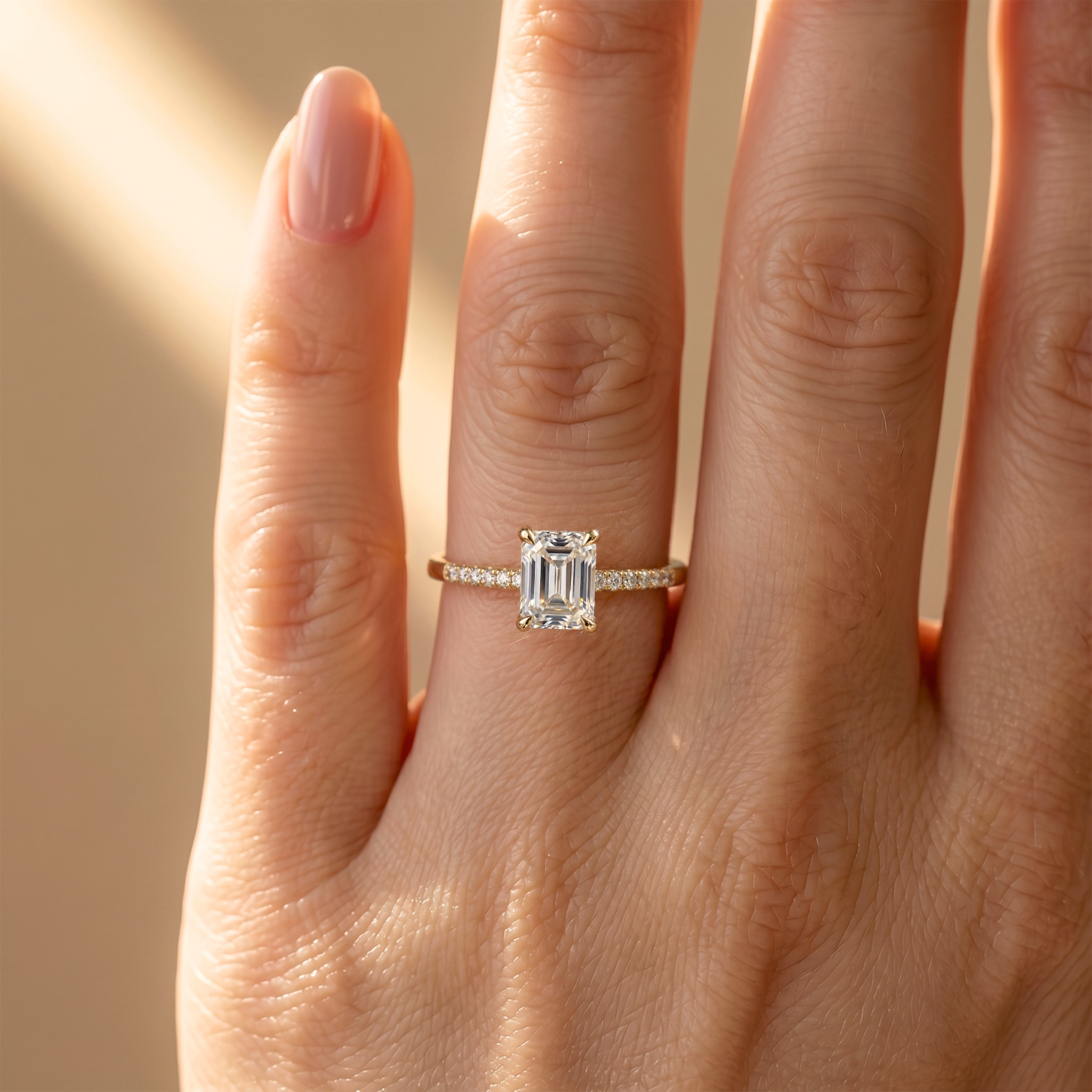 A close-up lifestyle shot highlighting the delicate sparkle of the yellow gold emerald-cut moissanite ring on a hand.