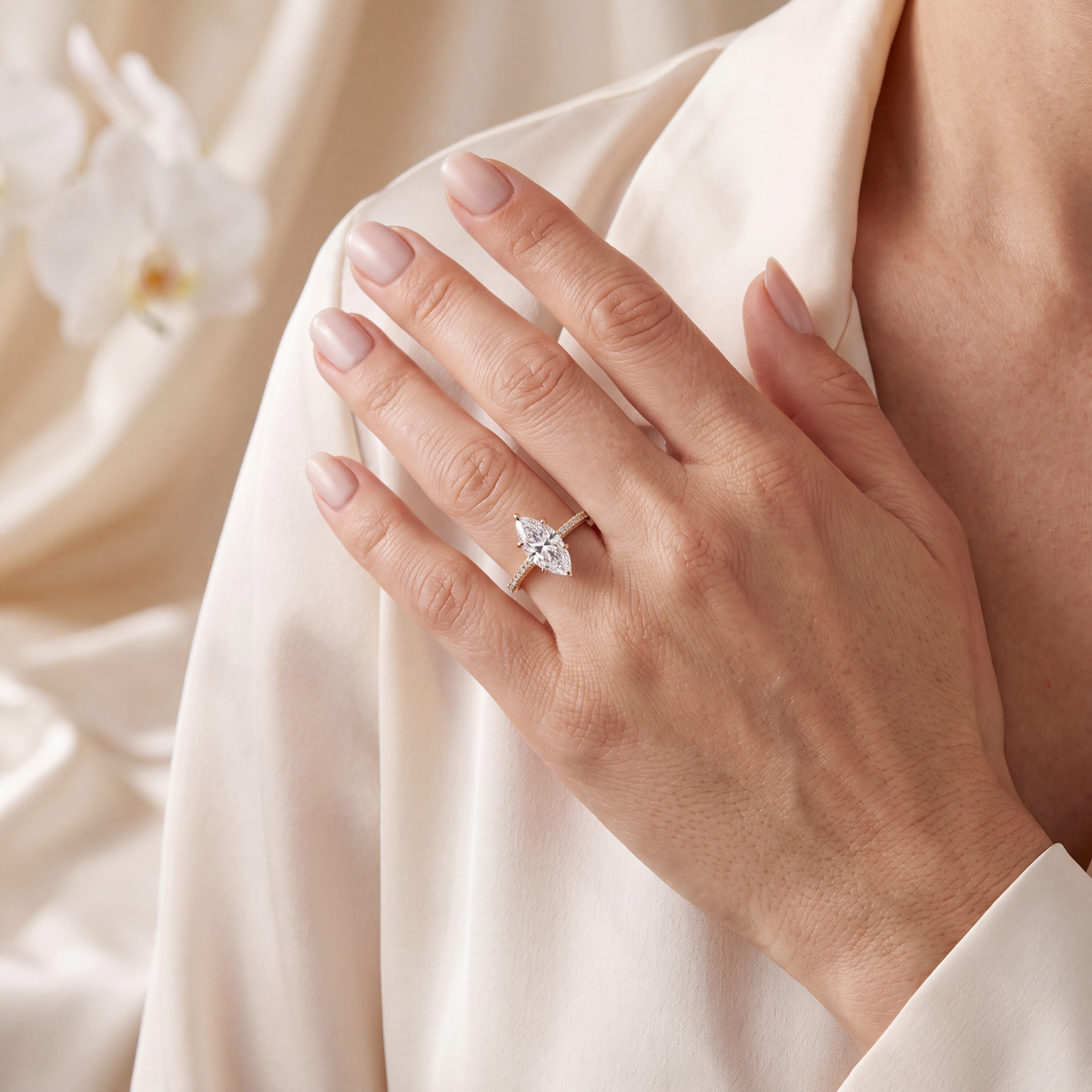 Model posing with her hand resting on her shoulder while wearing a yellow gold marquise moissanite ring.