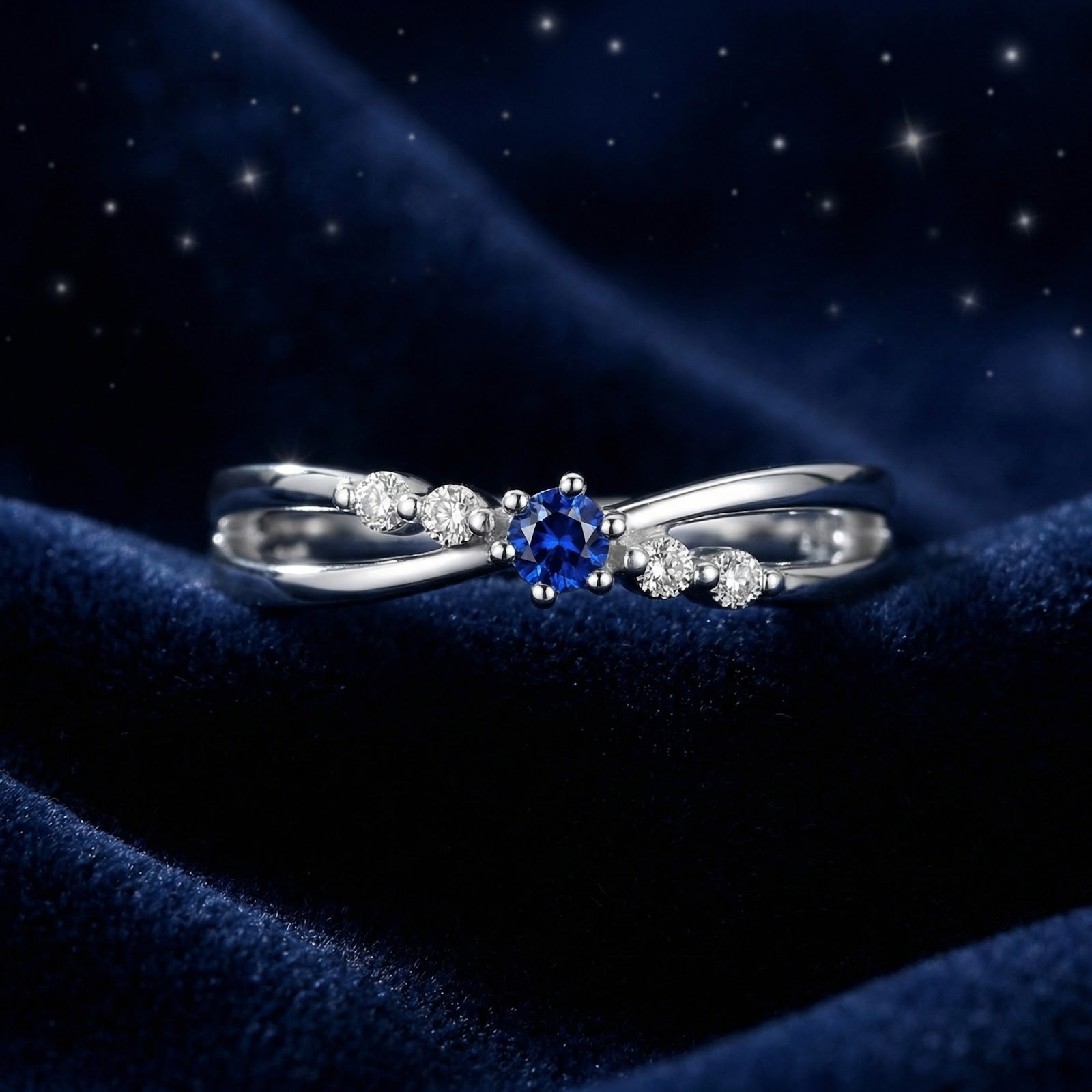 Isaraea S925 sterling silver twist ring with a round royal blue simulated sapphire on a starry blue velvet background.
