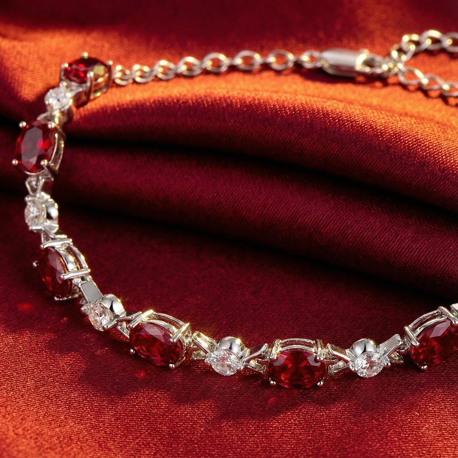 Close-up of oval-cut pigeon blood simulated rubies and white accent stones in a sterling silver tennis bracelet.