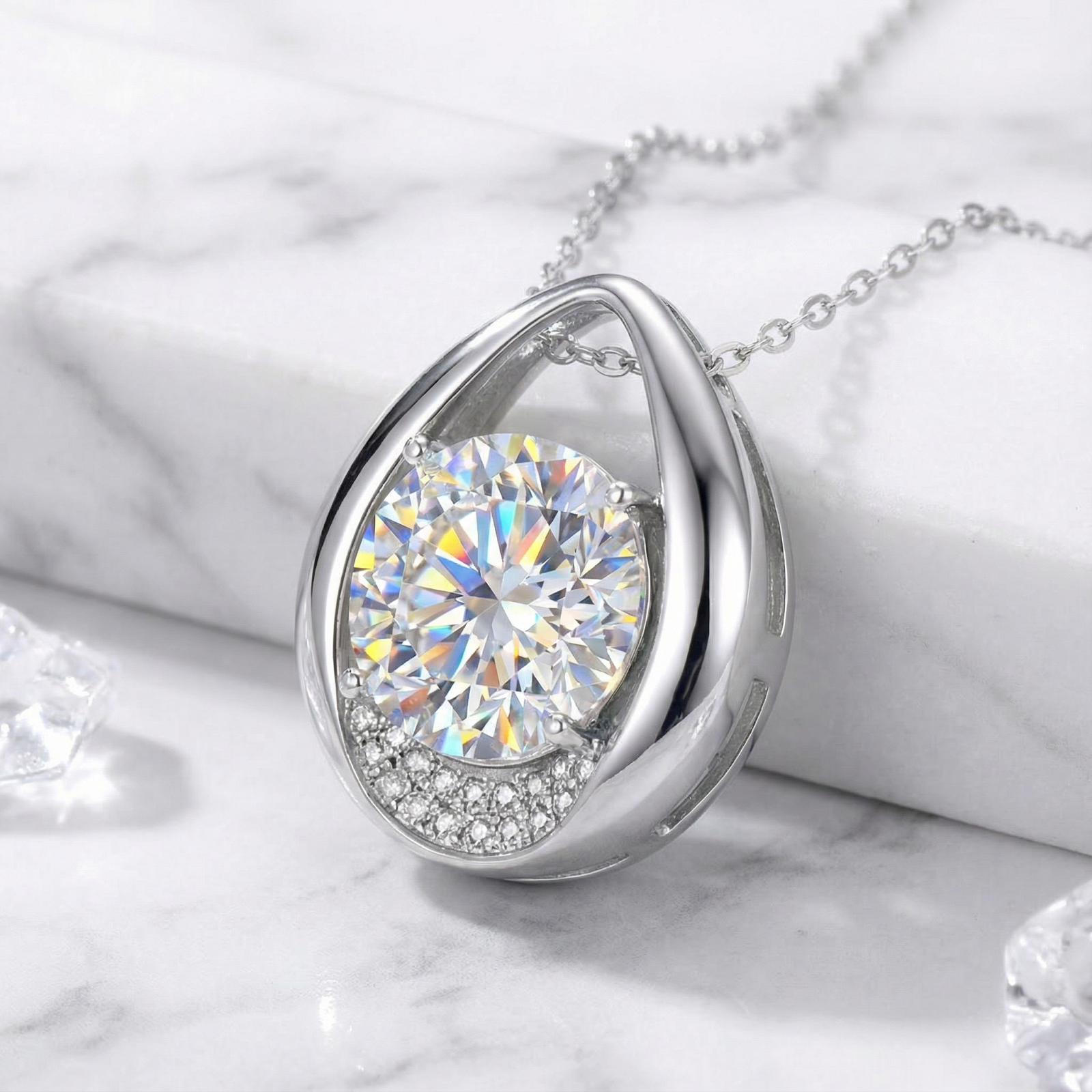Close-up of the Arwenna teardrop necklace in sterling silver with a brilliant round cut zirconia on marble.