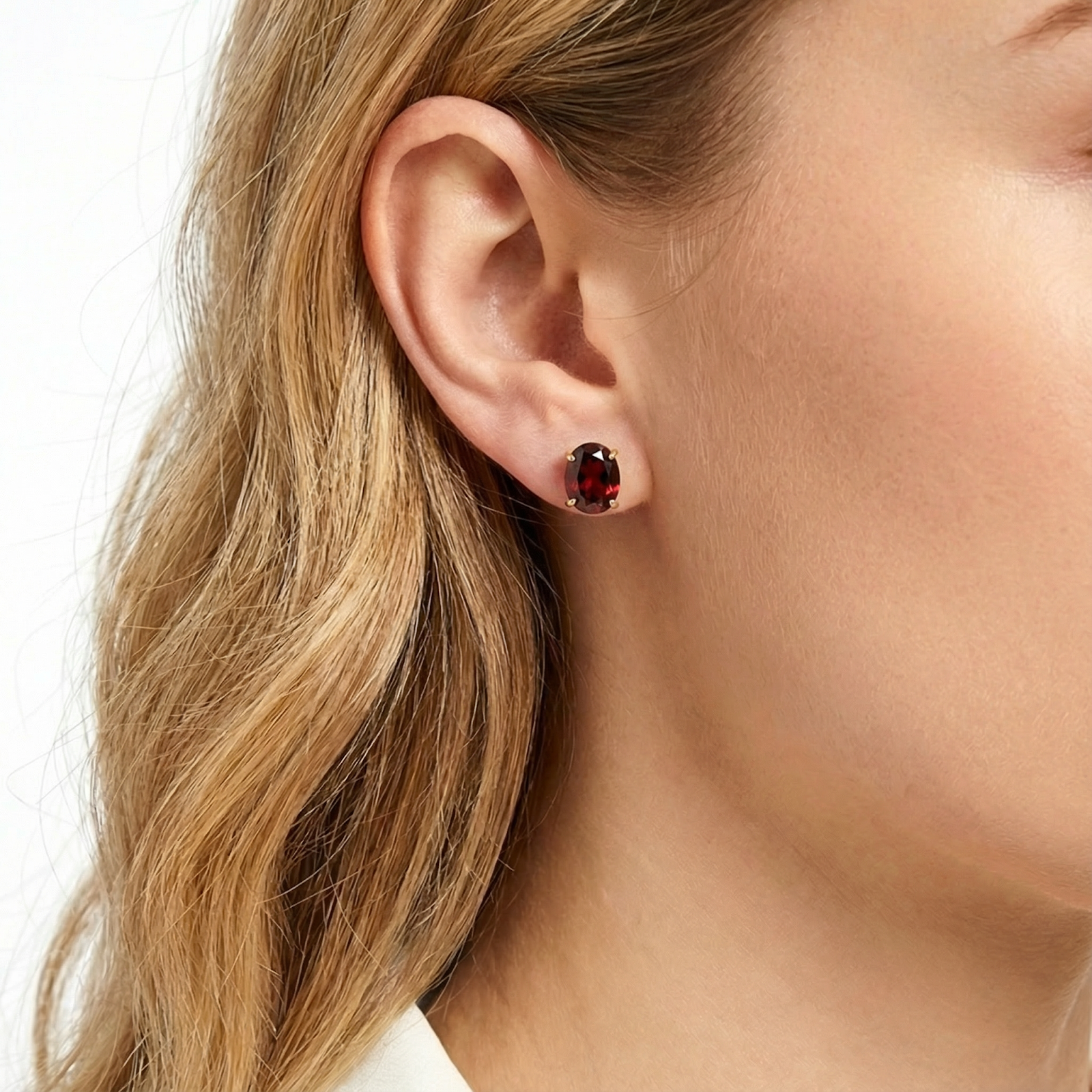 Blonde woman wearing a Seraphine 18K gold vermeil stud earring with a deep red simulated garnet stone.
