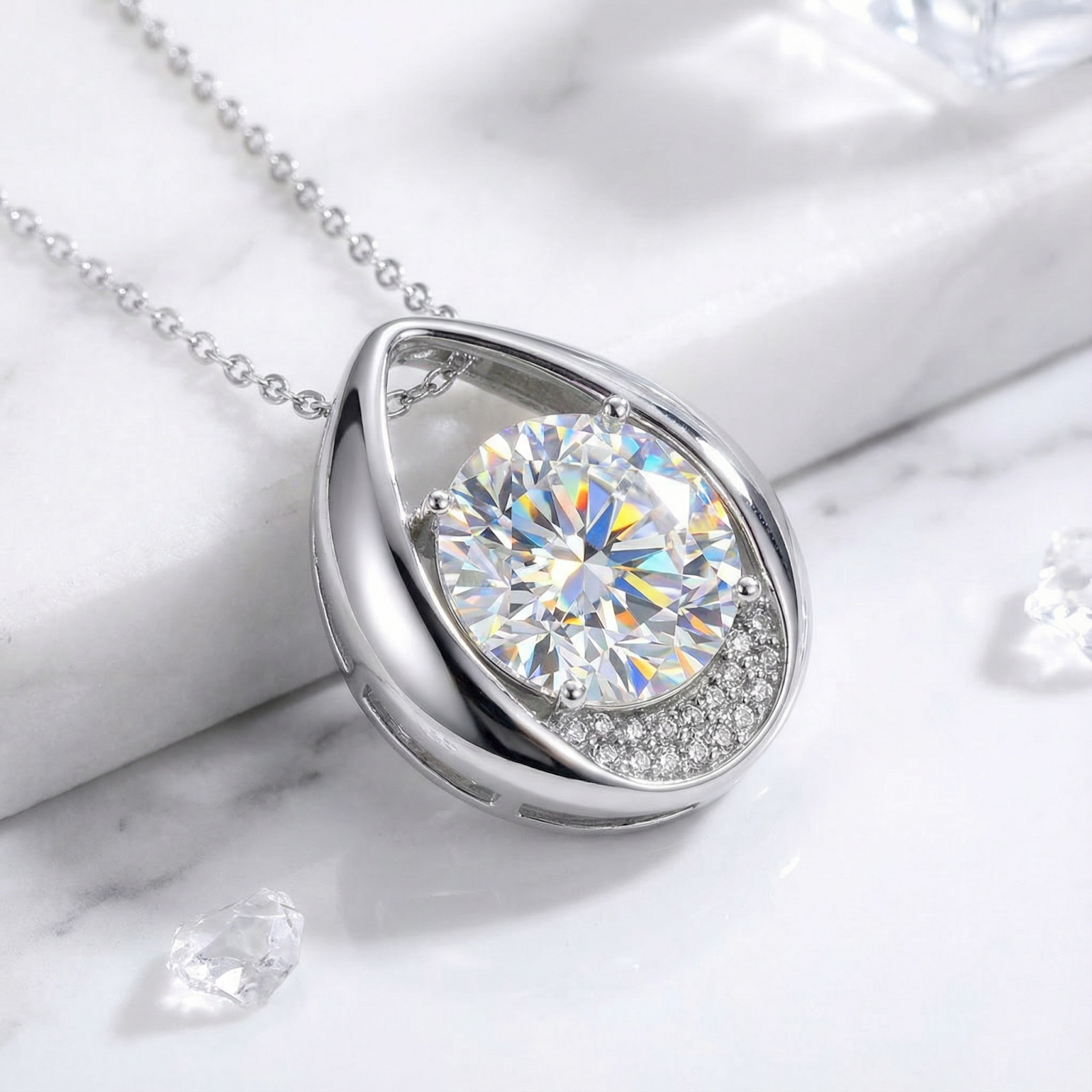Side view of the sterling silver teardrop necklace featuring a round cut zirconia on a marble surface.