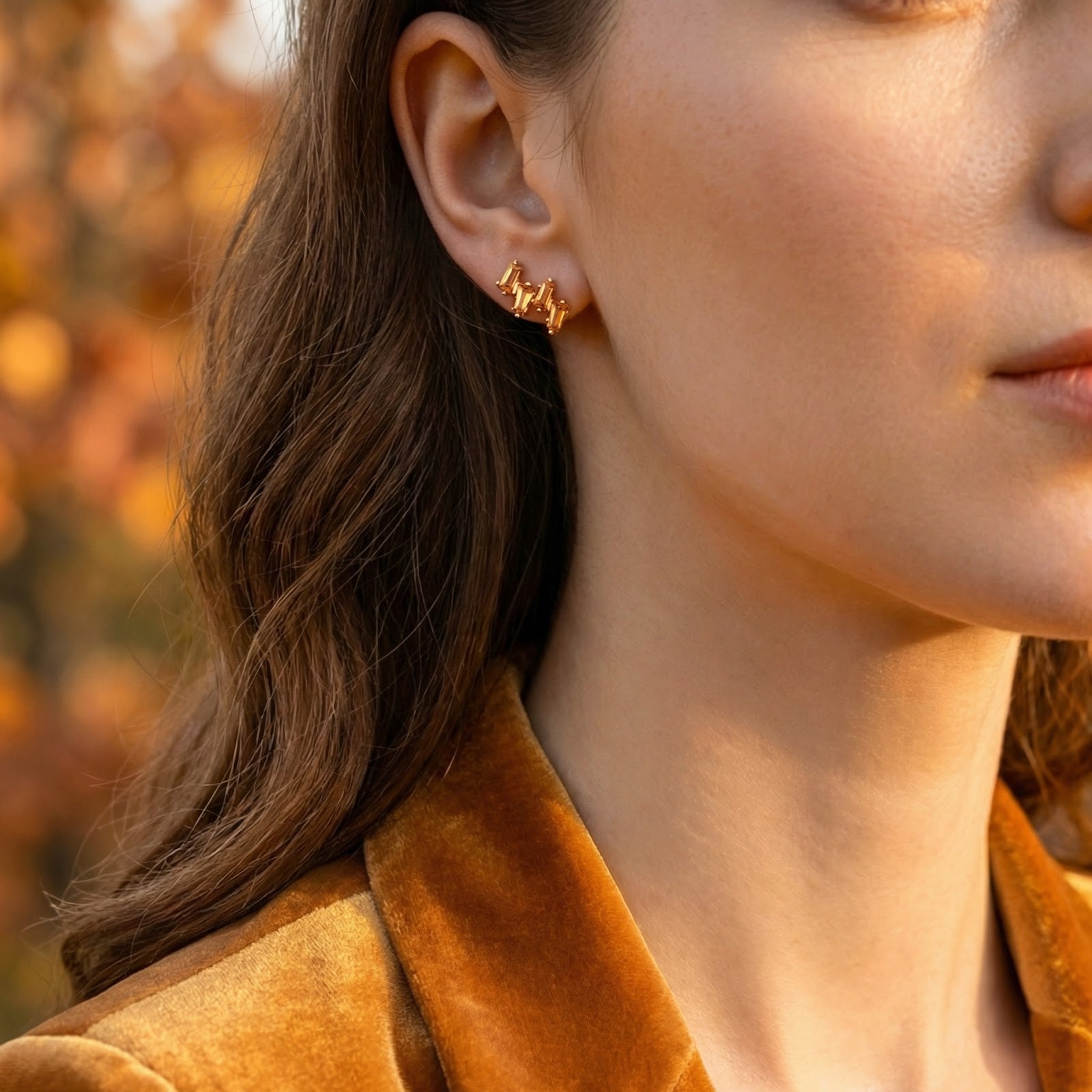 Side profile of a woman wearing a Lyranelle 18K gold vermeil cluster earring with honeyed simulated topaz stones.