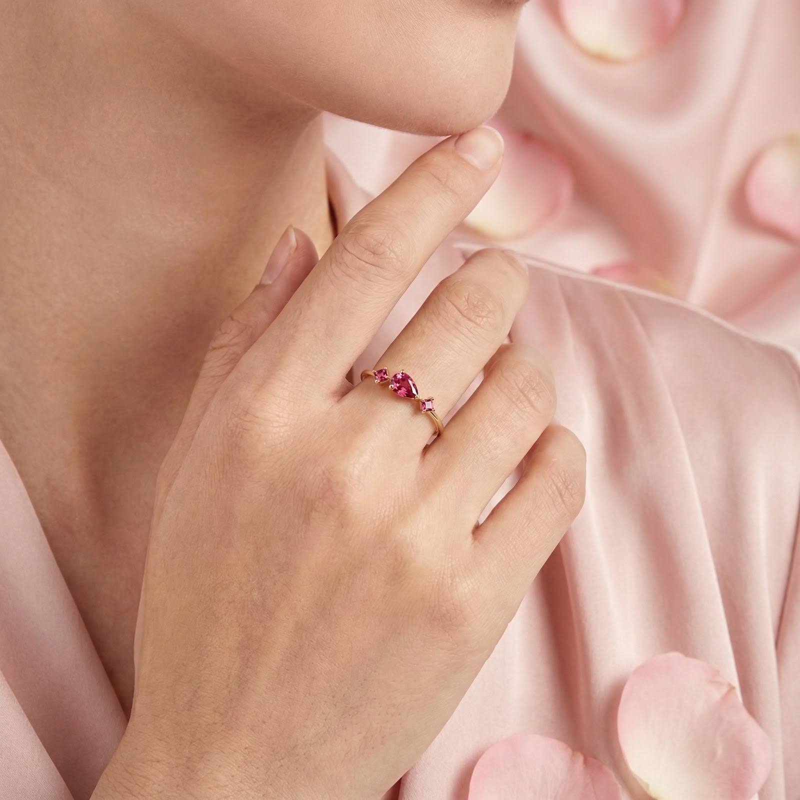 18K gold vermeil pink tourmaline ring worn on a model's hand against a pink silk background.