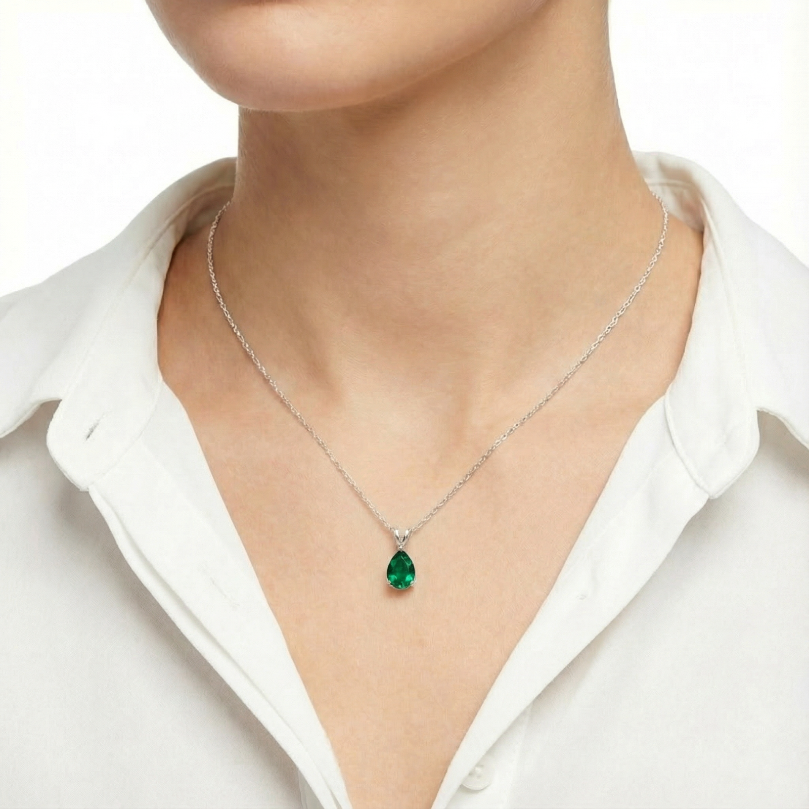 Model wearing the Valeska pear-cut green moissanite necklace in sterling silver with a white button-down shirt.