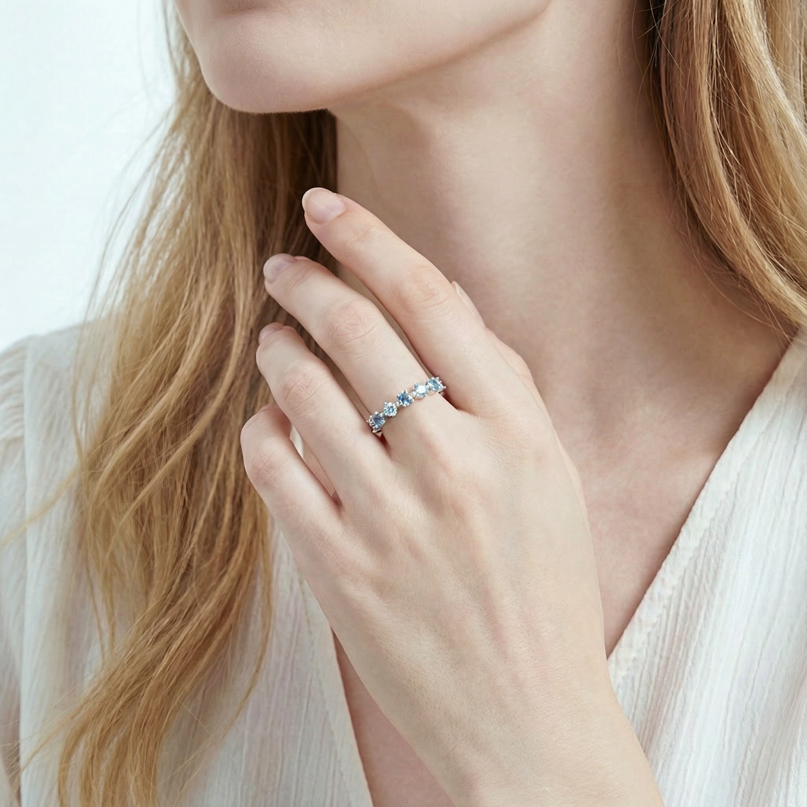 Woman wearing the Thalassa sterling silver half-eternity ring with round cut simulated aquamarine stones.