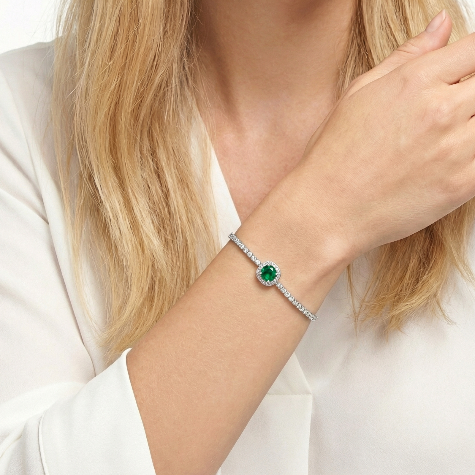 Detailed view of the sterling silver Eveline bracelet with a green simulated emerald on a woman's wrist.