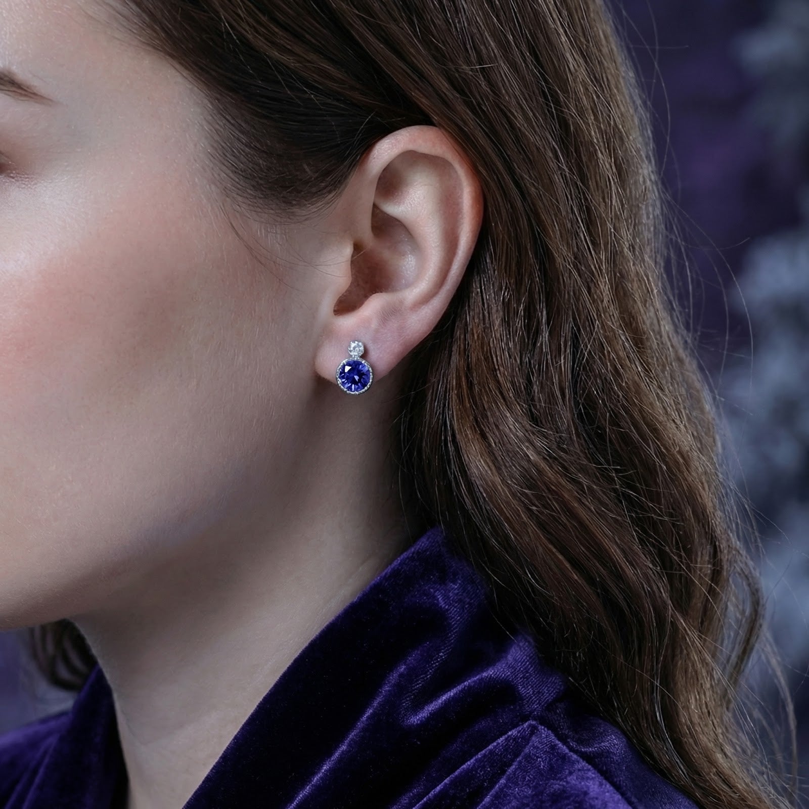 Model wearing a round simulated tanzanite and sterling silver drop earring on her ear.