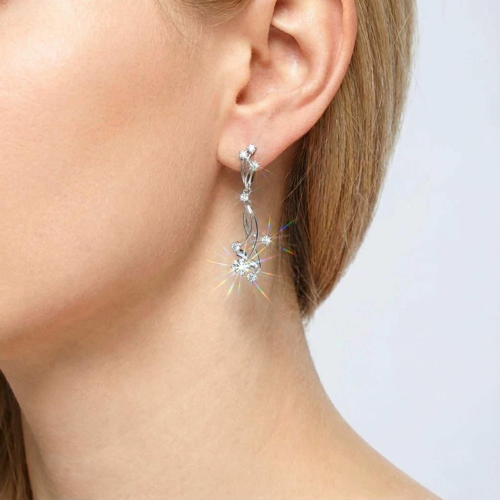 Close-up of a silver vine drop earring with round zirconia stones worn on a model's ear.