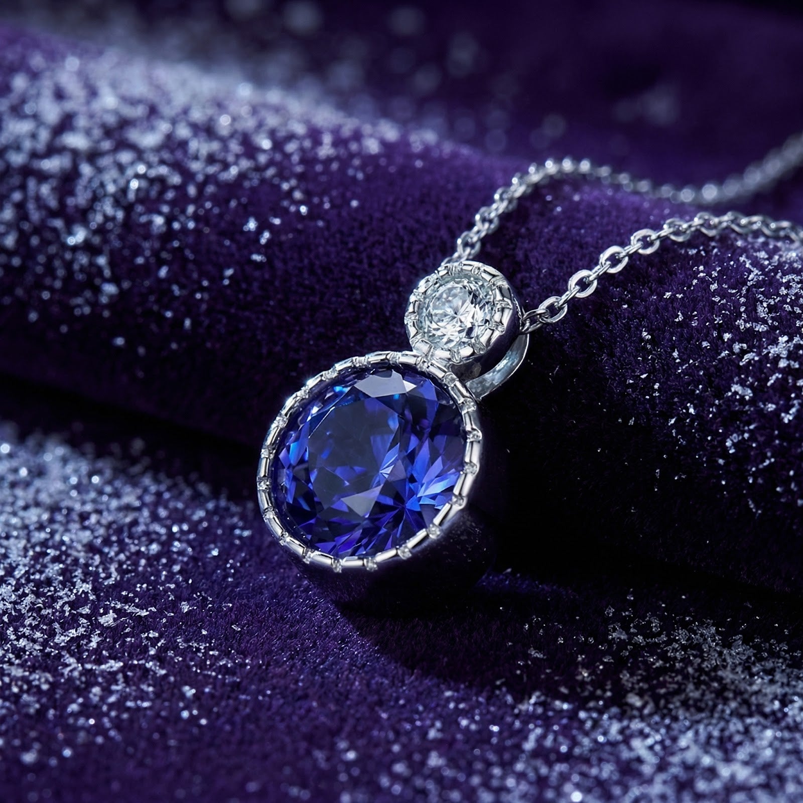 Macro shot of the round-cut simulated tanzanite pendant and sterling silver setting on purple velvet.