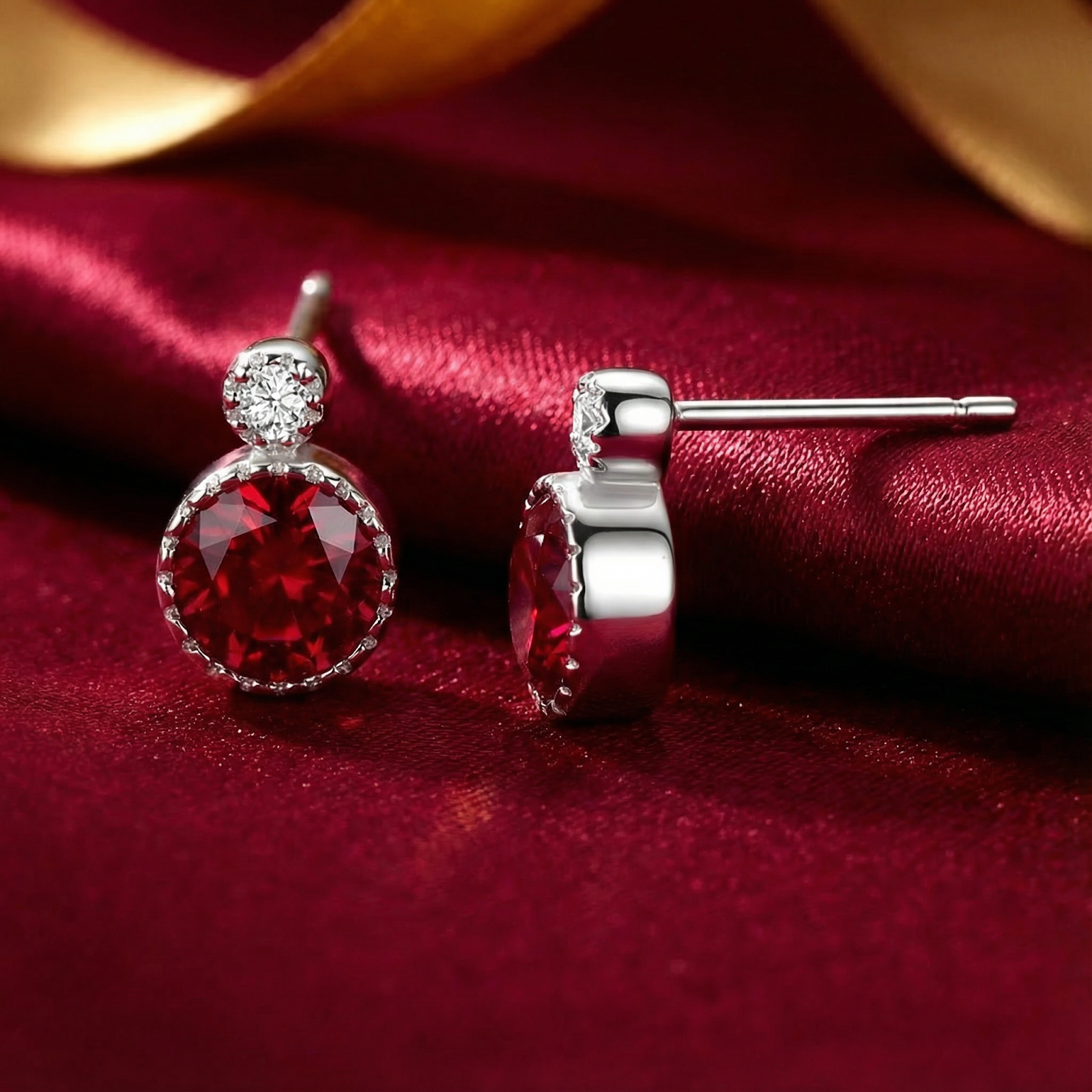 Side profile and front view of round cut simulated ruby stud earrings in sterling silver on red silk.