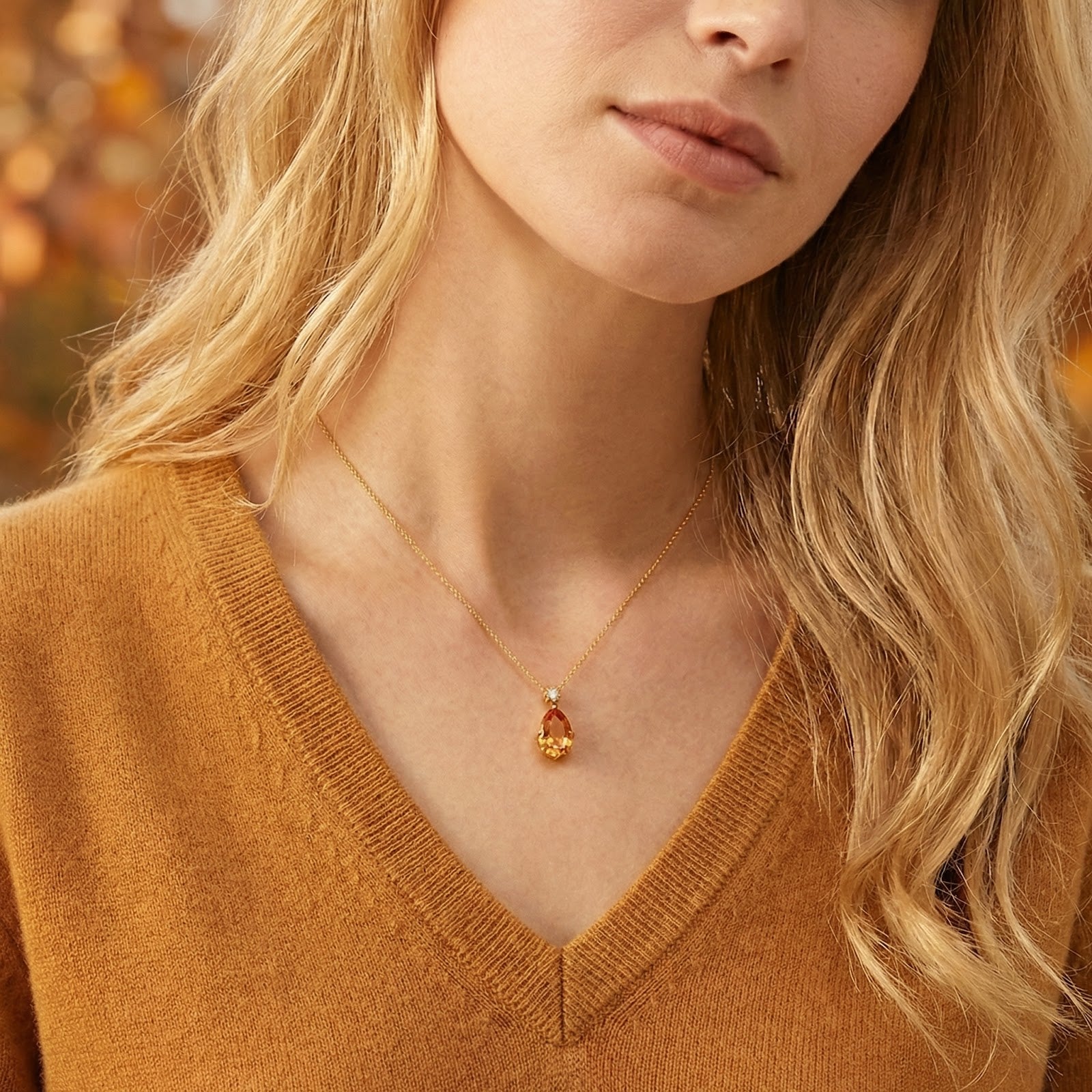 Aurelienne pear-cut simulated topaz necklace in 18K gold vermeil worn by a model in a gold knit sweater.