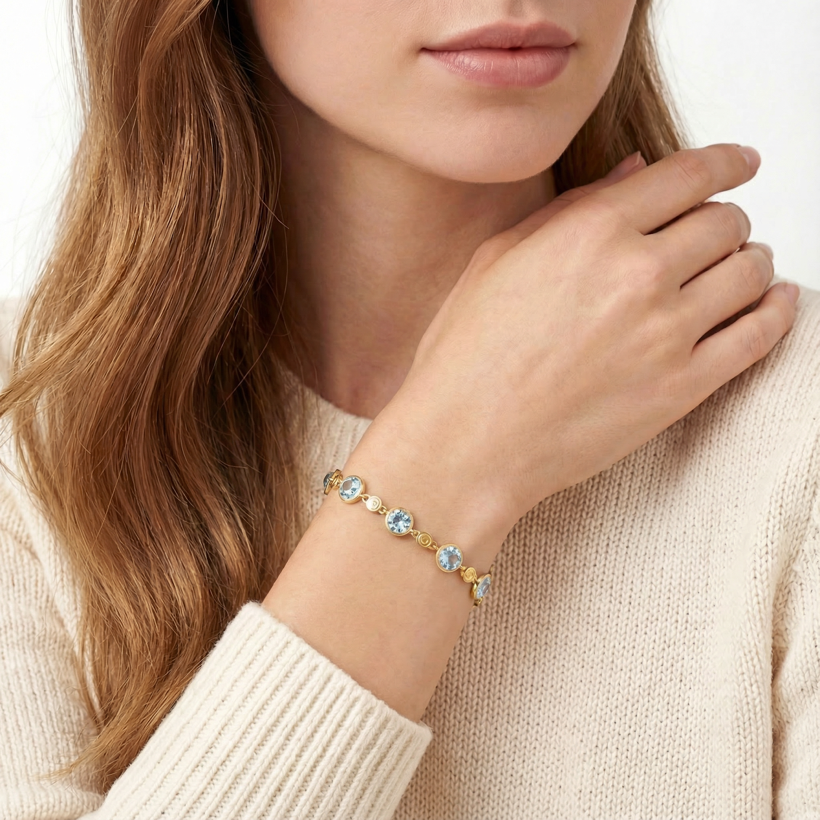 Woman wearing the Marisol 18K gold vermeil station bracelet with light blue simulated aquamarine stones.