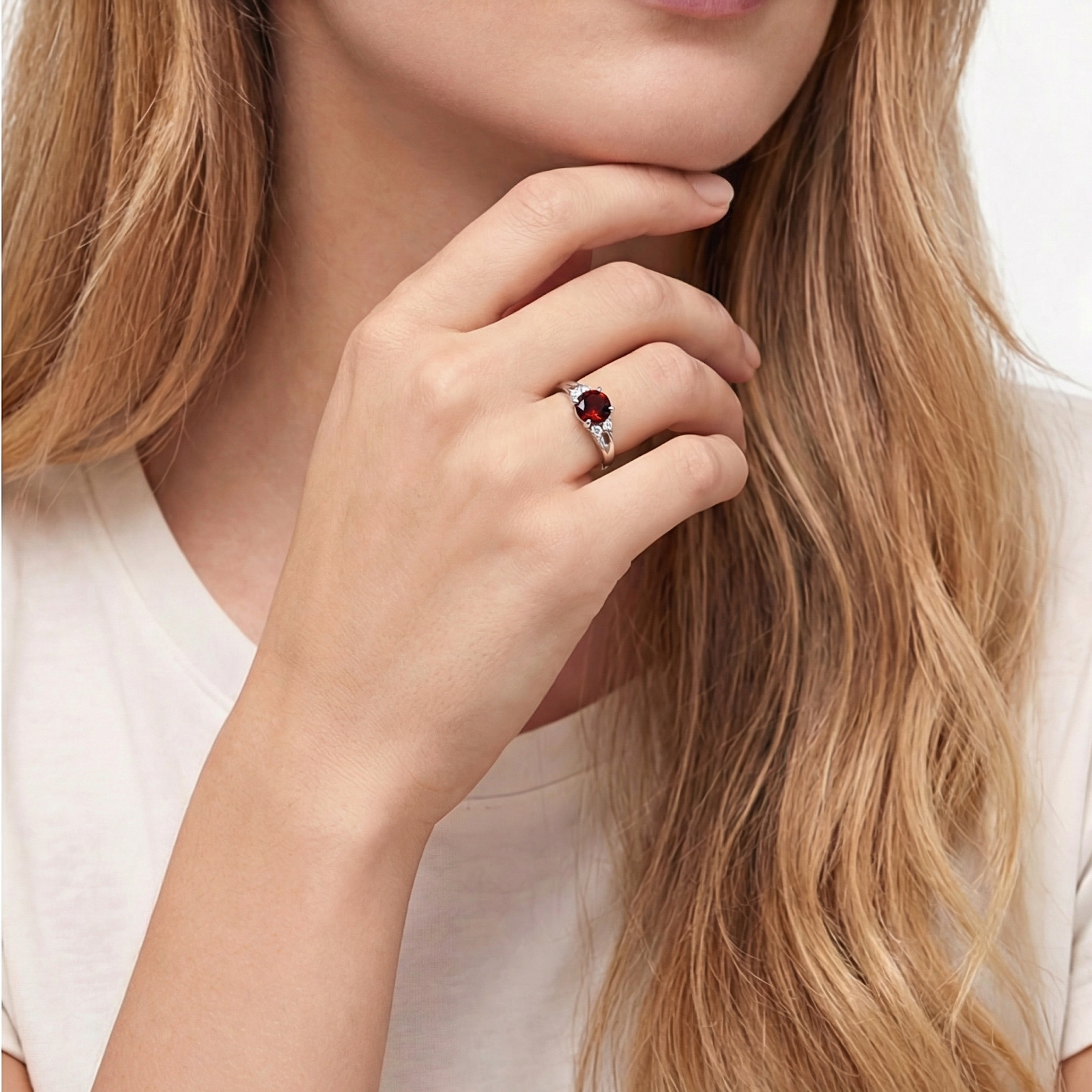 Model wearing the sterling silver bypass ring with a round red garnet stone against a white shirt.