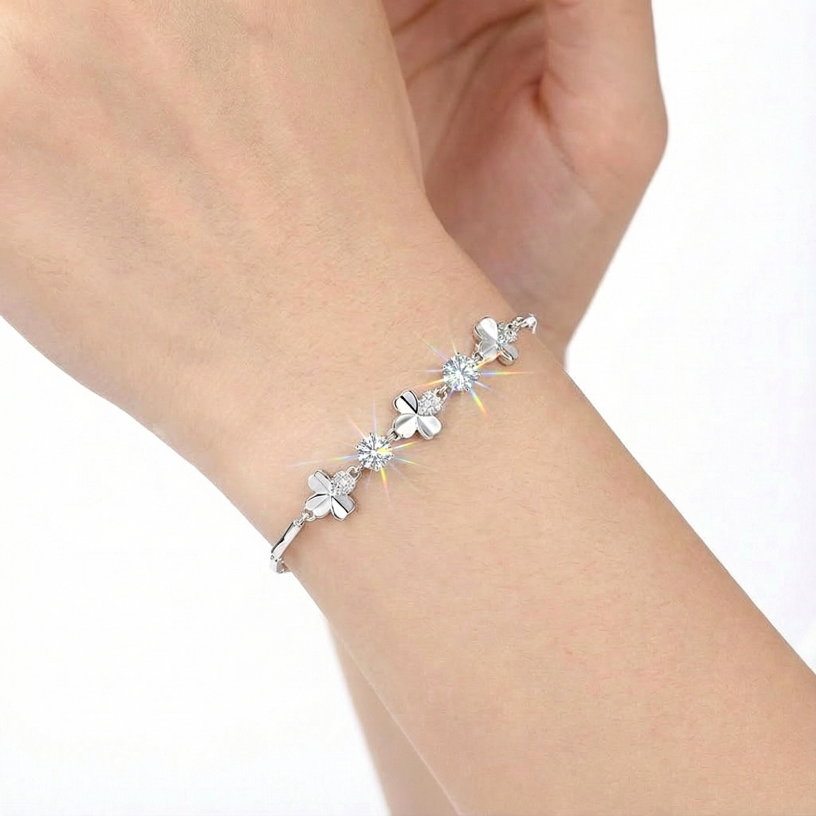 Close-up of the silver clover bracelet with brilliant round-cut simulated diamonds worn on a woman's wrist.