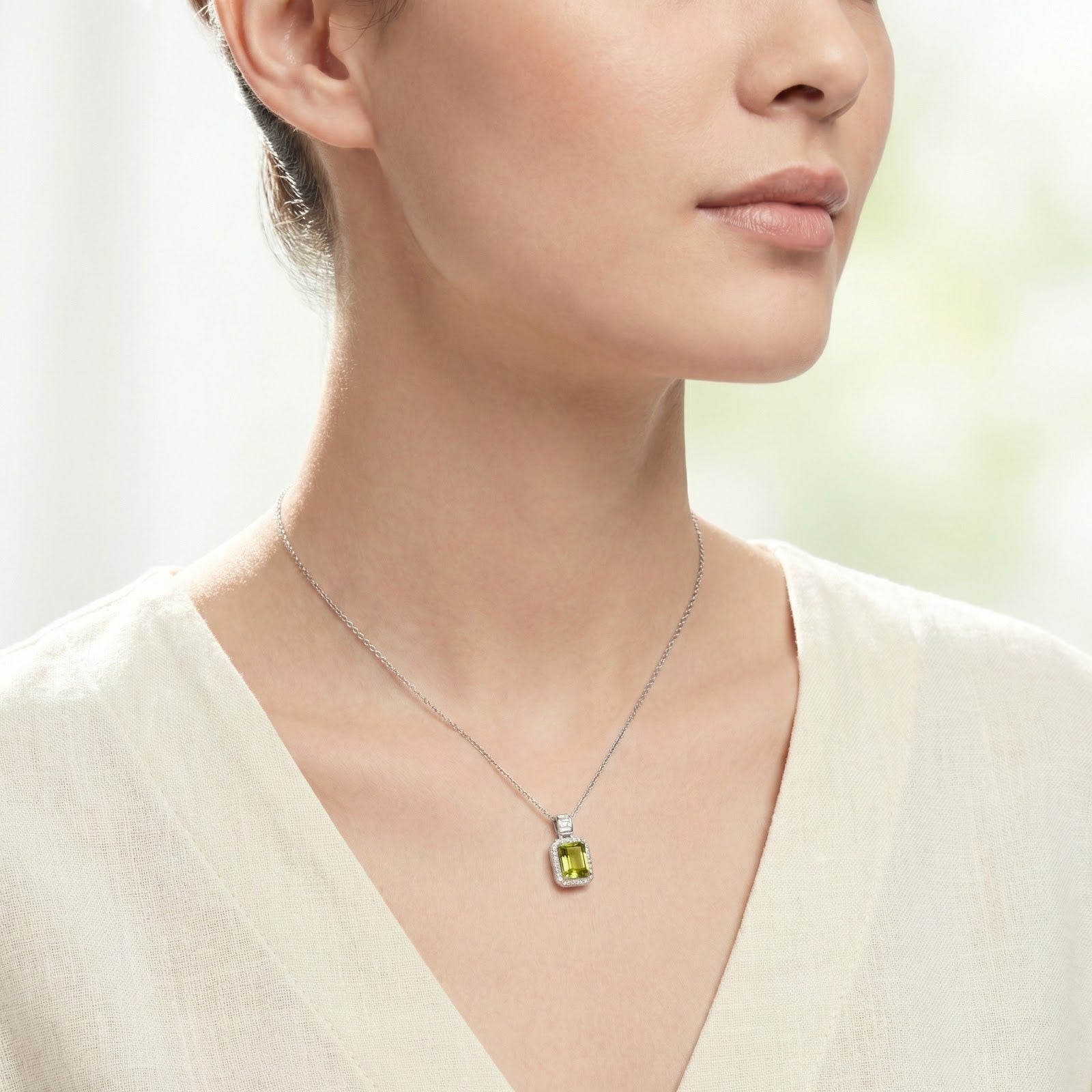 Model wearing the emerald-cut simulated peridot pendant necklace in sterling silver against a soft background.