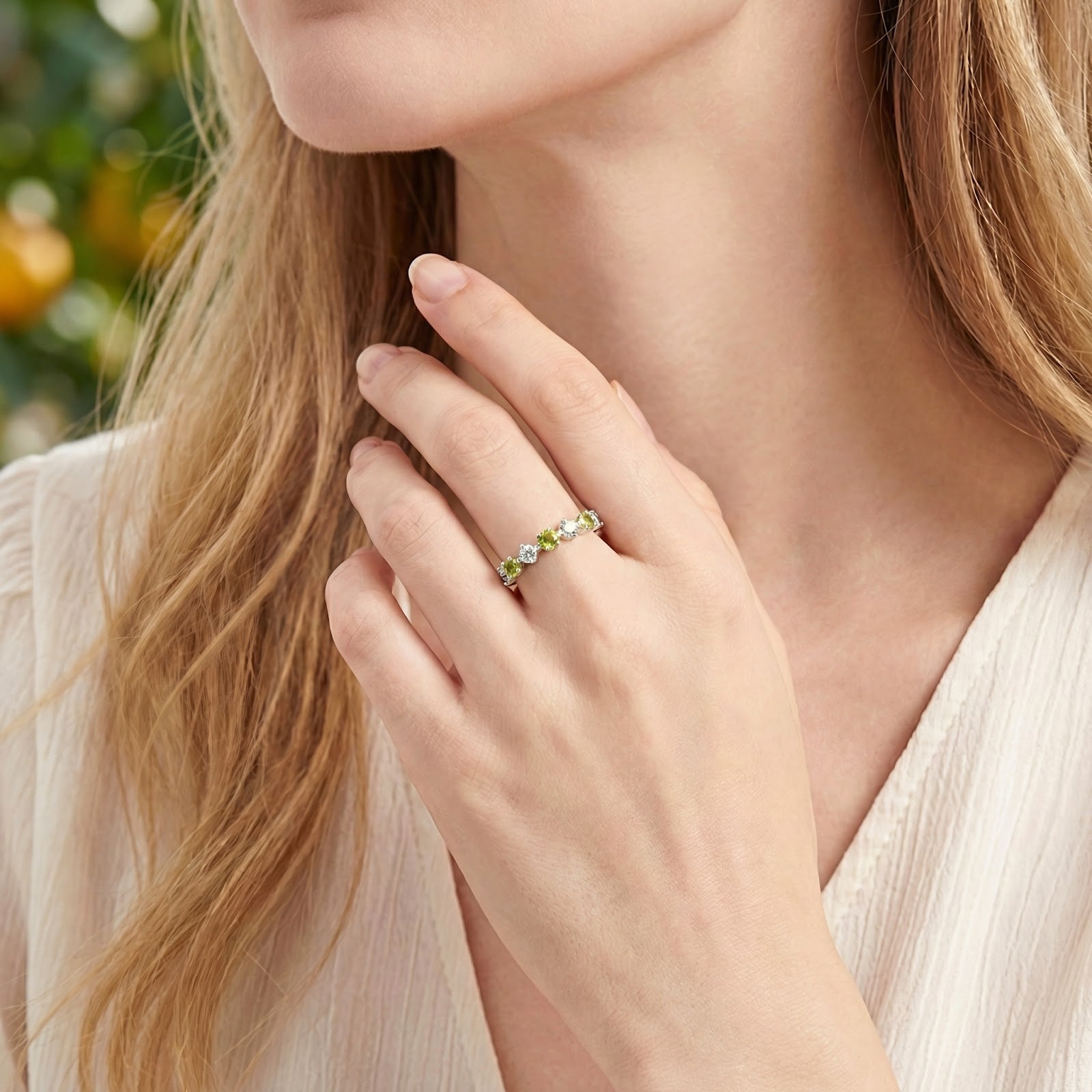 Sterling silver simulated peridot and clear stone ring worn on a woman's hand.