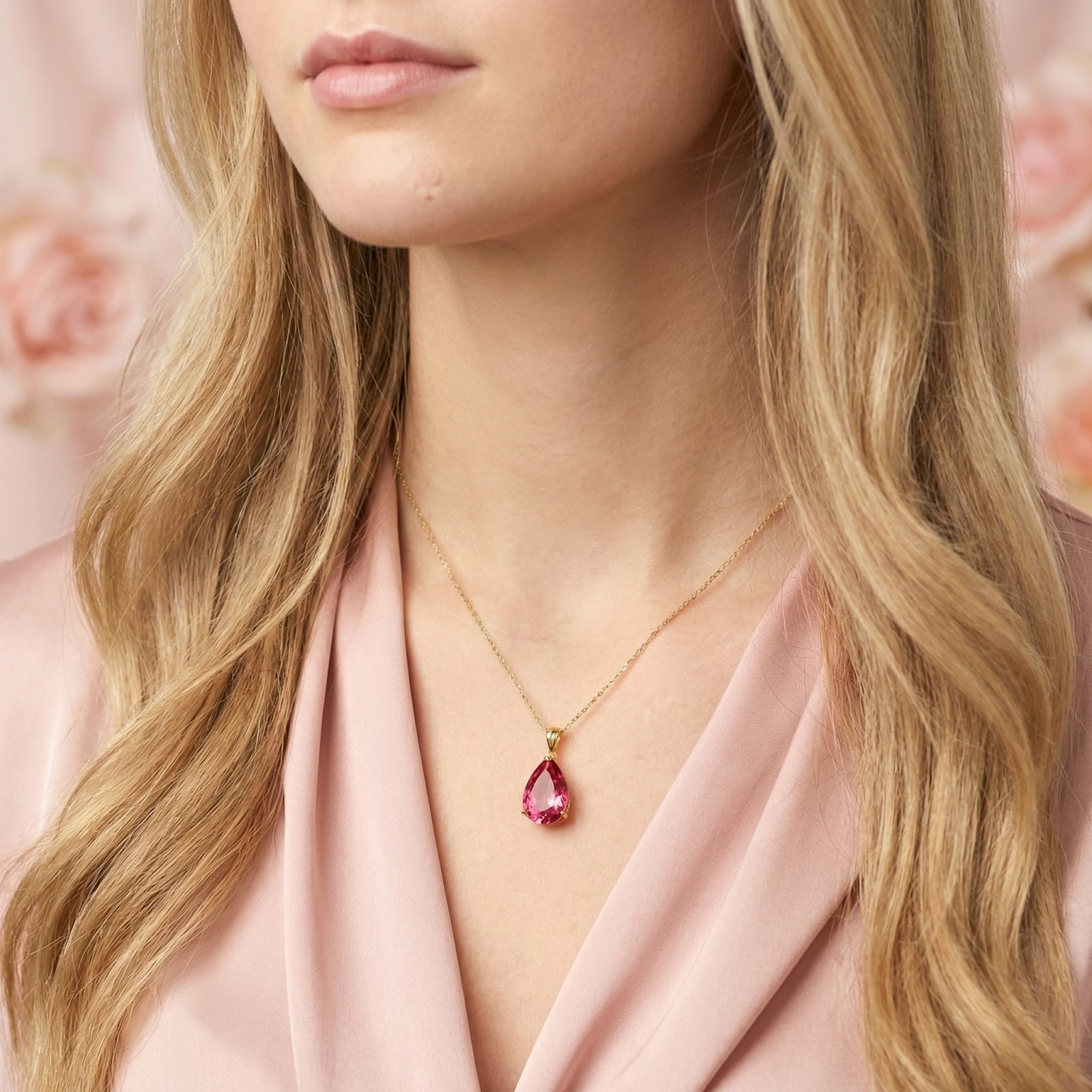 Close-up of a model wearing a pear-cut simulated pink tourmaline pendant on an 18K gold vermeil chain.