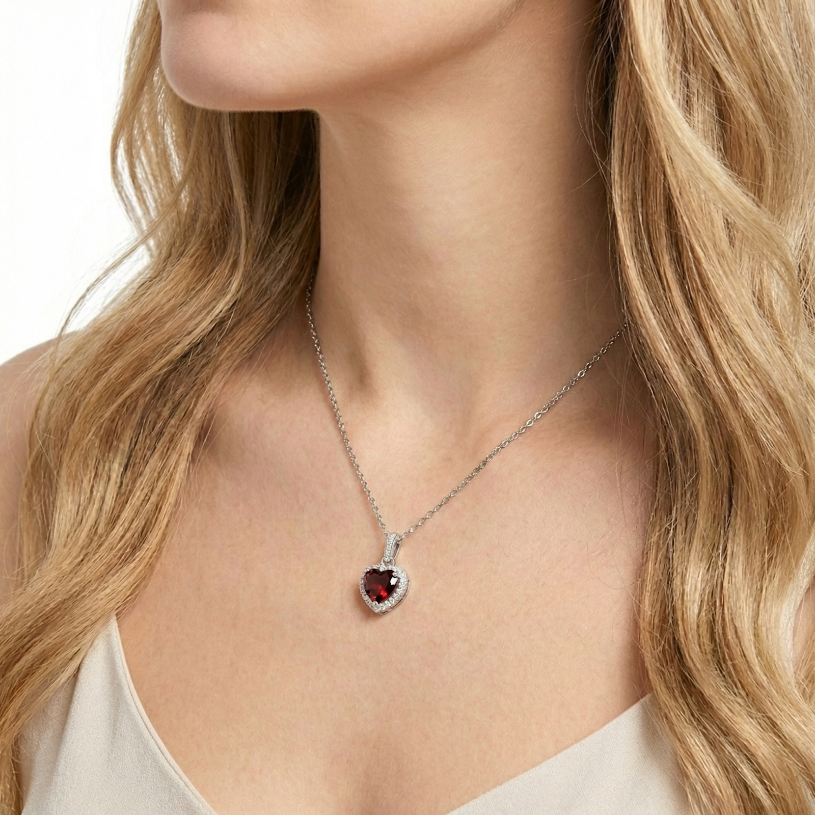 Close-up of a woman wearing the heart-cut red garnet halo pendant on a sterling silver chain.