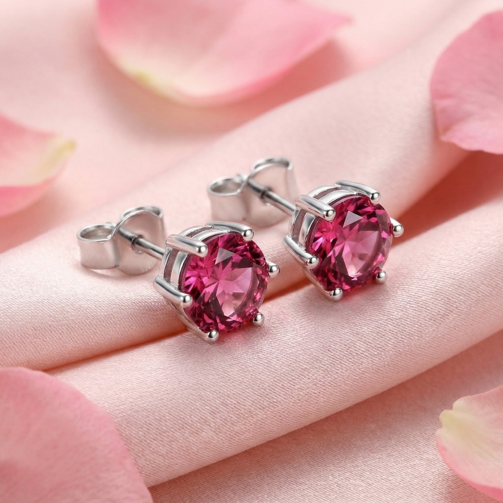 Round cut simulated pink tourmaline stud earrings in sterling silver on pink silk with rose petals.