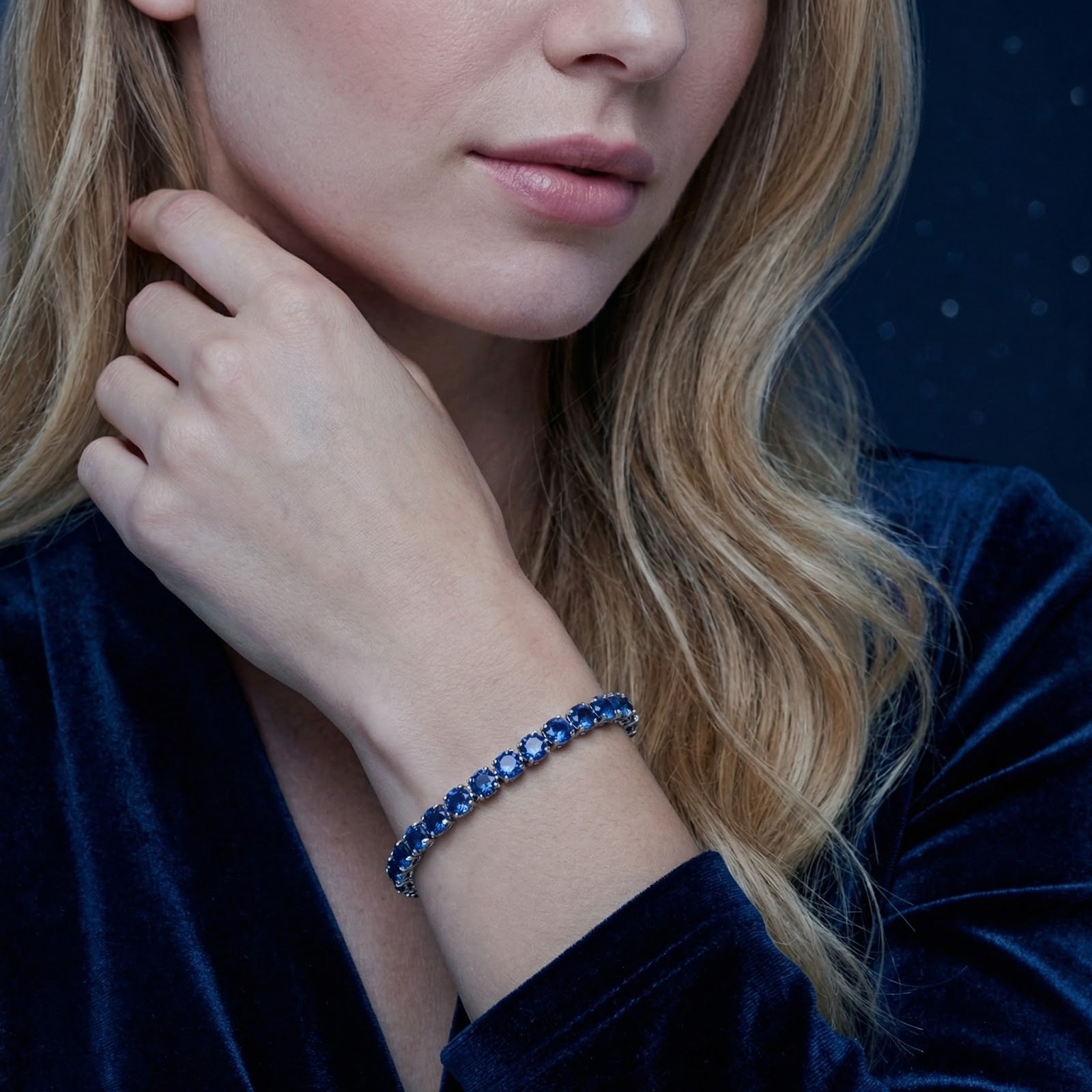 Royal blue simulated sapphire tennis bracelet in silver stainless steel worn on a woman's wrist.