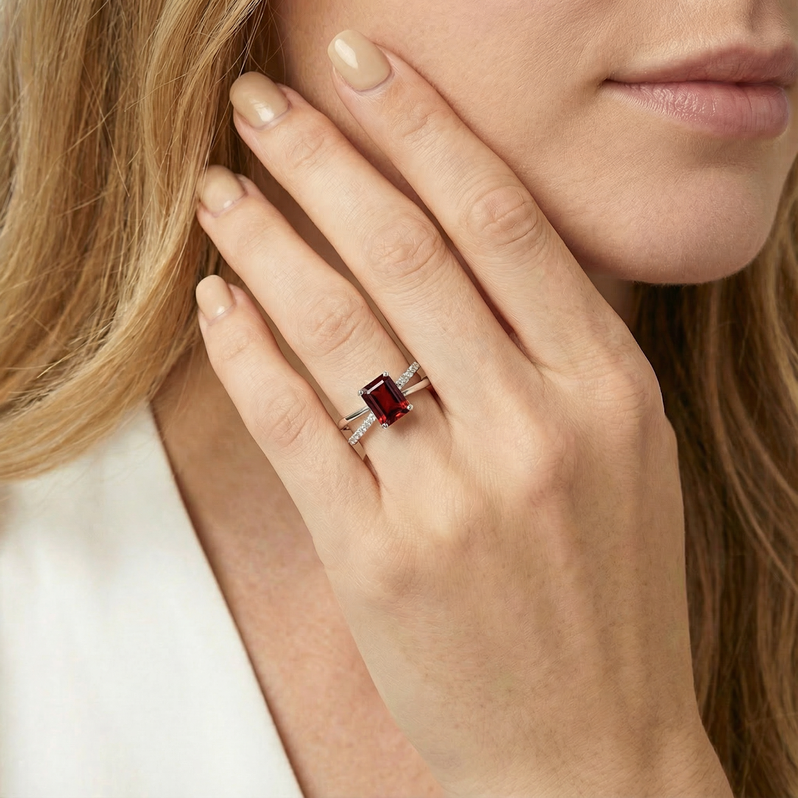 Emerald cut simulated garnet Isolt twist ring in S925 sterling silver worn on a woman's hand.