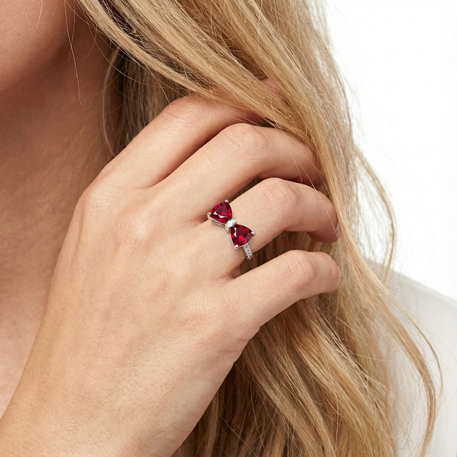 Vivara bow ring with trillion-cut simulated rubies in S925 sterling silver worn on a model's hand.