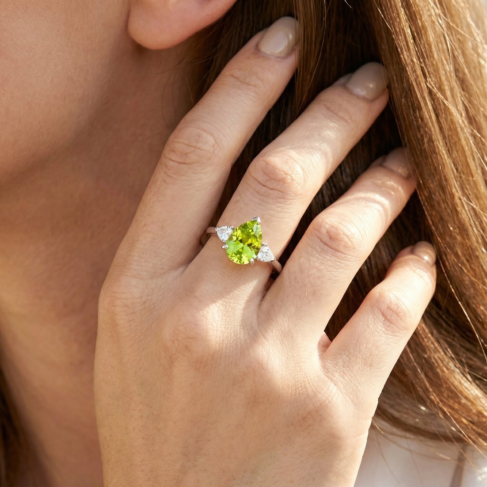 Pear-cut simulated peridot sterling silver ring displayed on a woman's ring finger.