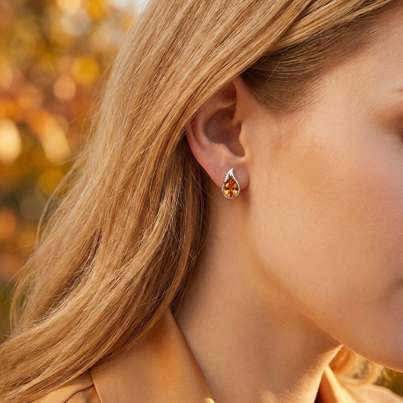 Woman wearing Melisara Bud sterling silver and round-cut simulated topaz earrings in an outdoor autumn setting.