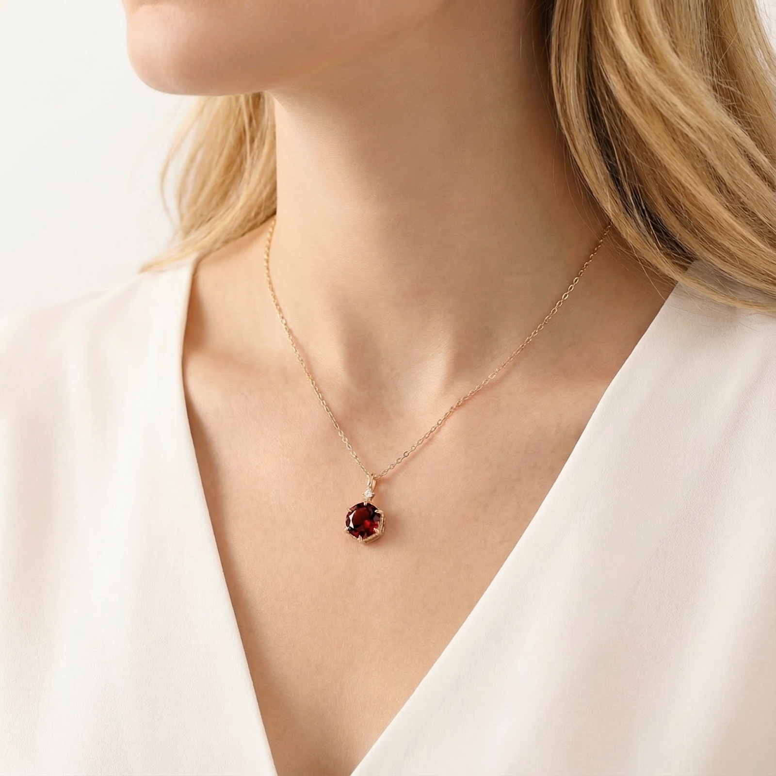 Close-up of a woman wearing the Kyra Hex 18K gold vermeil necklace with a deep red hexagon cut simulated garnet.