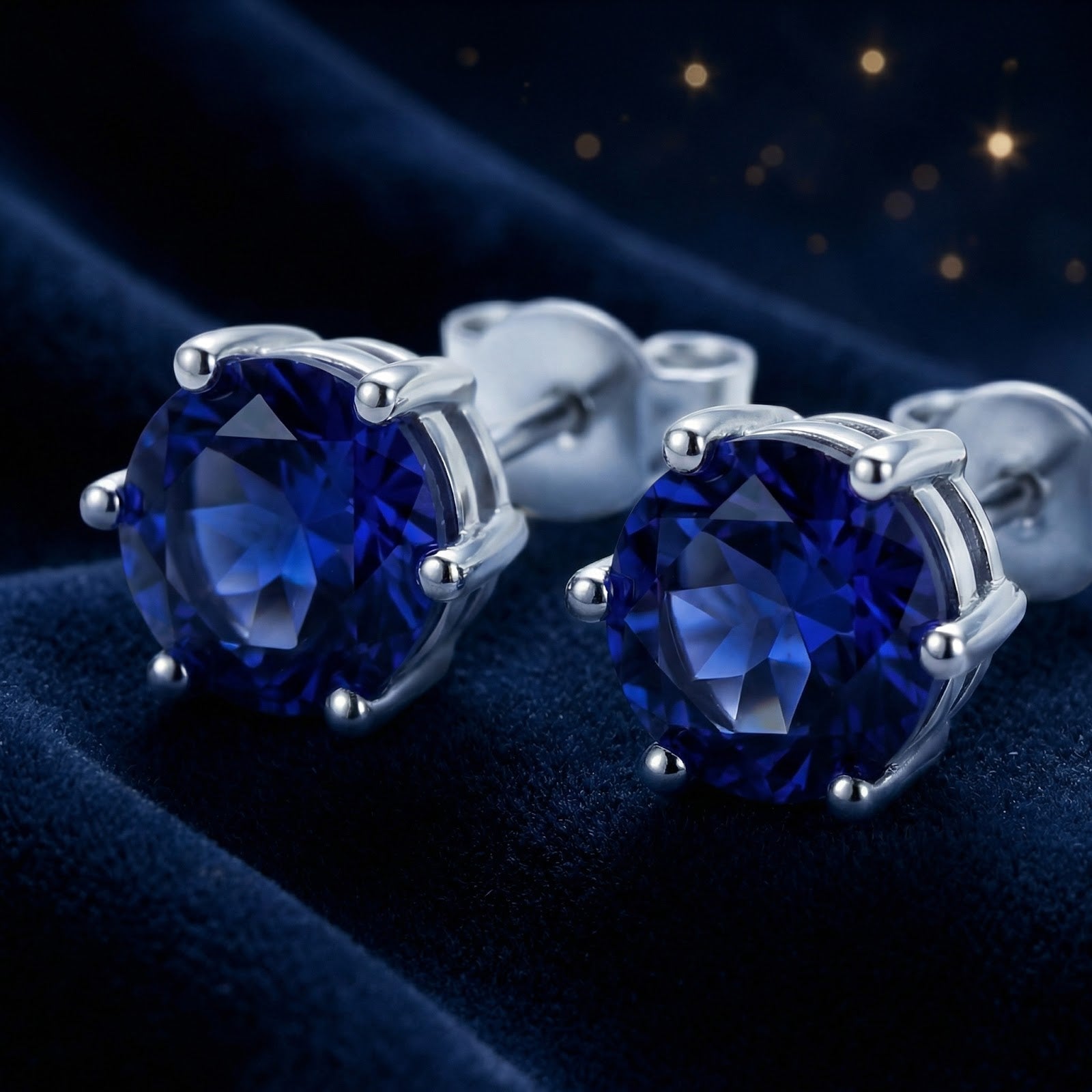 Macro view of round cut royal blue simulated sapphire studs with sterling silver prong settings.