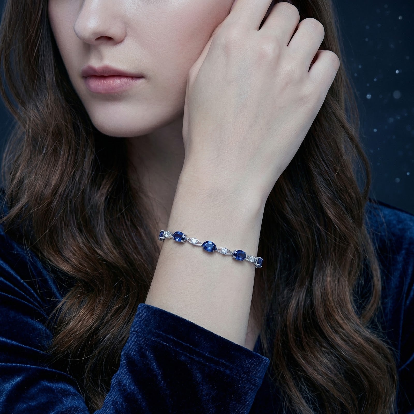 Woman wearing the Alarissa Azure sterling silver bracelet with oval-cut simulated blue sapphires on her wrist.