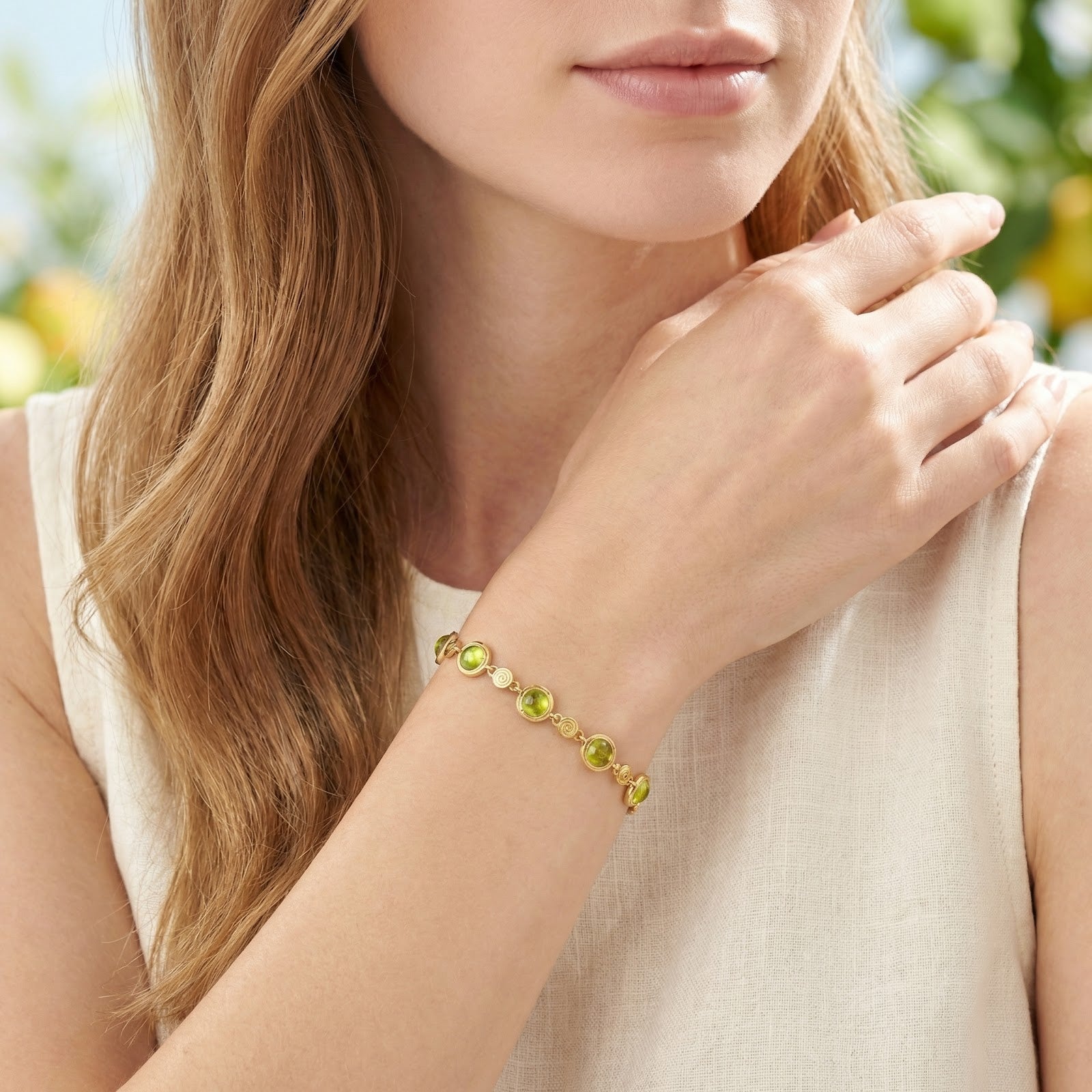 Woman wearing the 18K gold vermeil station bracelet with green simulated peridot stones on her wrist.