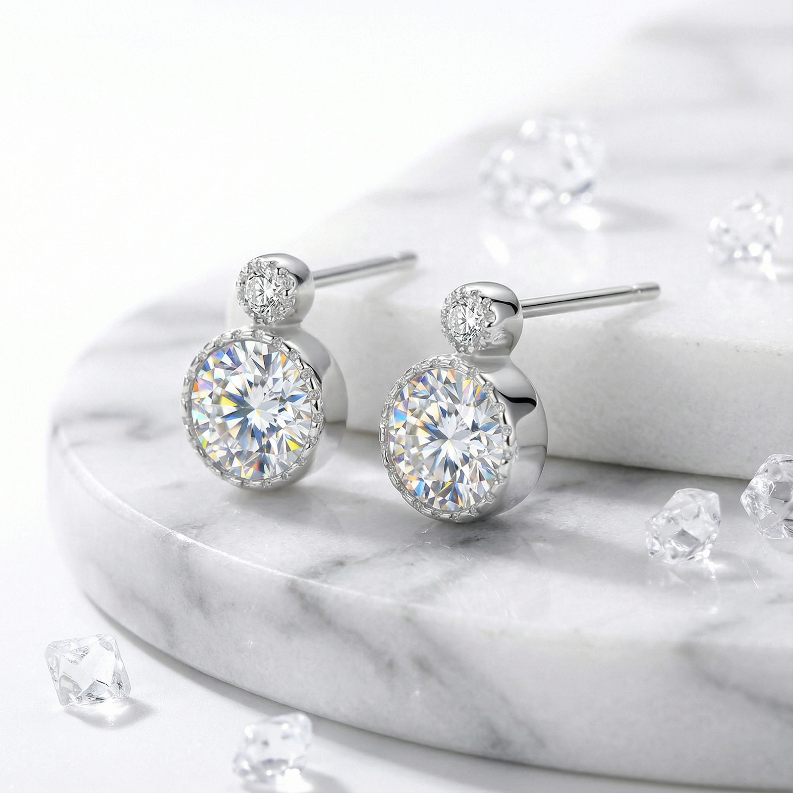 Pair of round cut simulated diamond studs in platinum vermeil silver on a circular marble display.