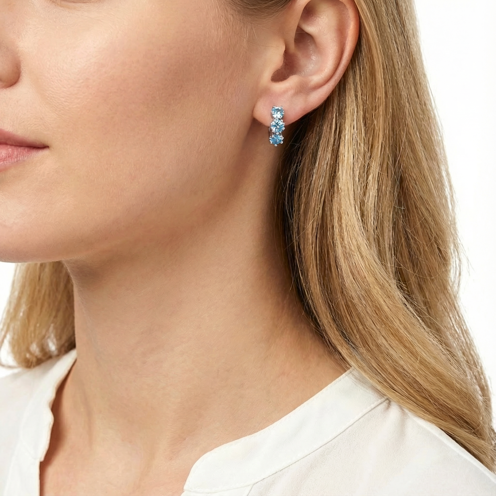 Side view of a model wearing the sterling silver Astra Star Hoops featuring light blue star-cut aquamarine stones.