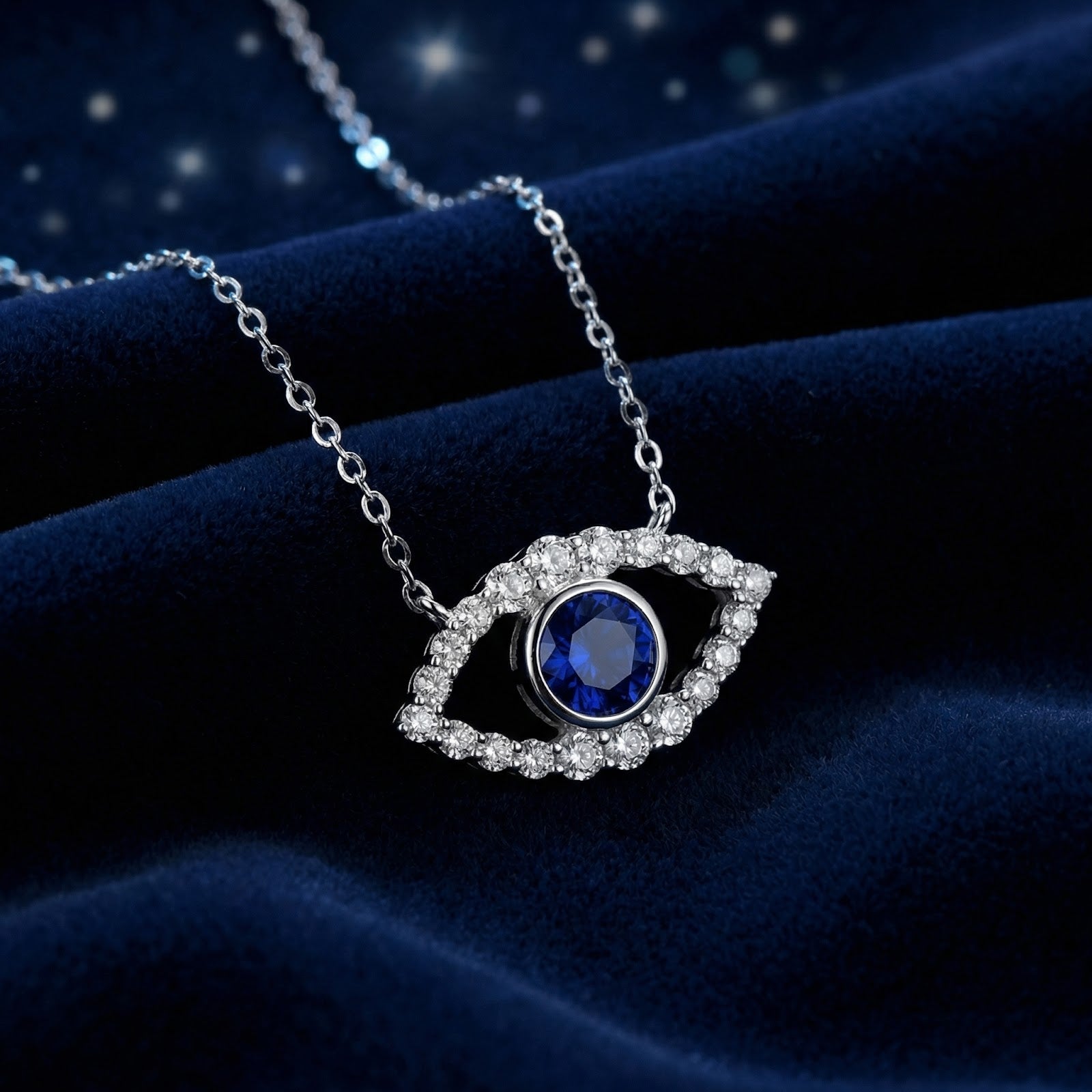 Sterling silver evil eye necklace with a round cut blue sapphire on dark blue velvet fabric.