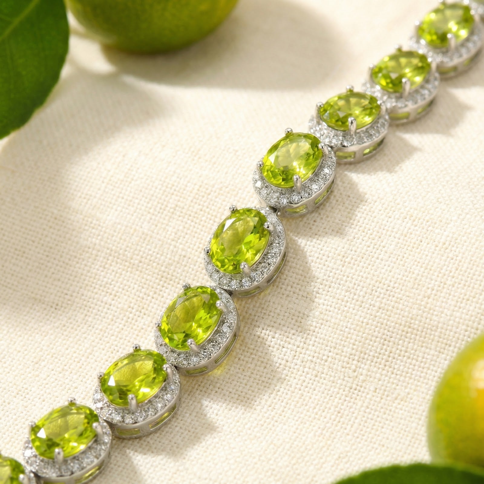 Macro view of oval cut simulated peridot stones in sterling silver halo settings on a tennis bracelet.