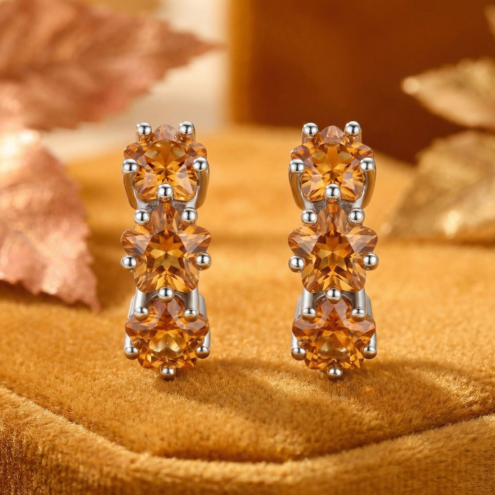 Close-up of Aurellise sterling silver huggies featuring three star-cut honeyed simulated topaz stones.