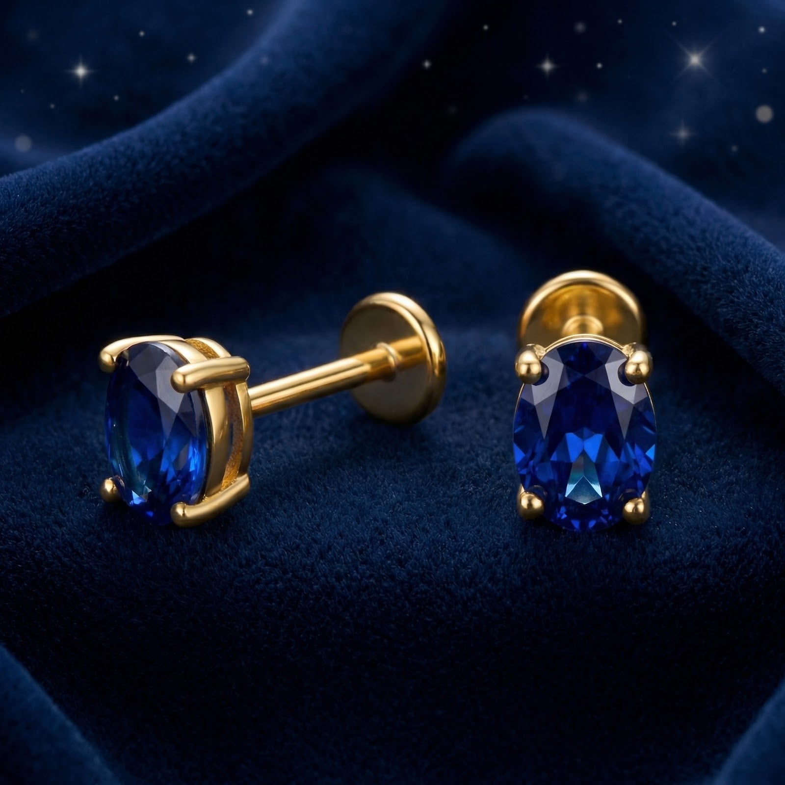 Oval cut royal blue simulated sapphire stud earrings in 18K gold vermeil showing flat back post on blue velvet.