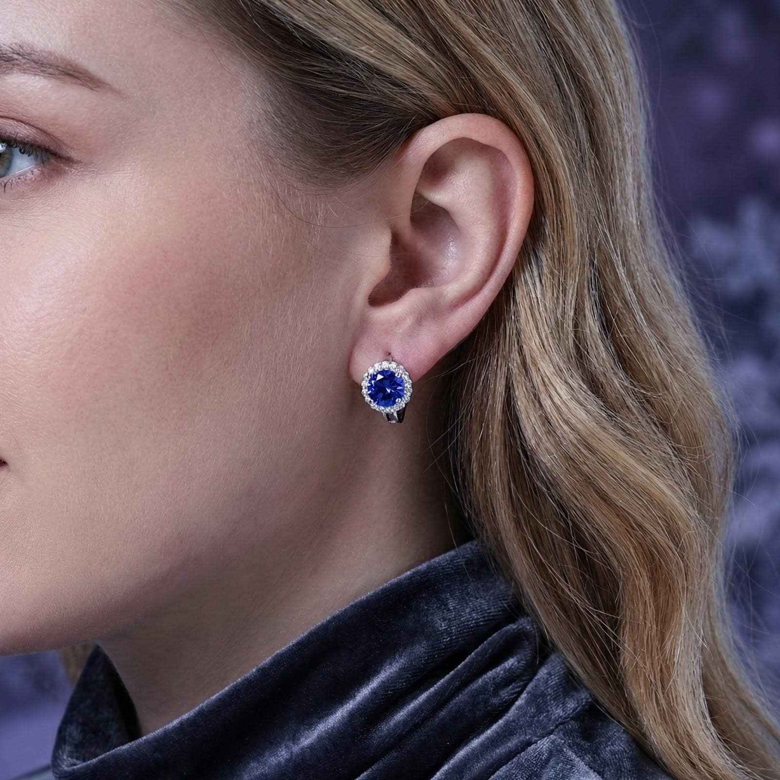 Woman wearing a round blue-violet moissanite halo stud earring in S925 sterling silver, profile view.